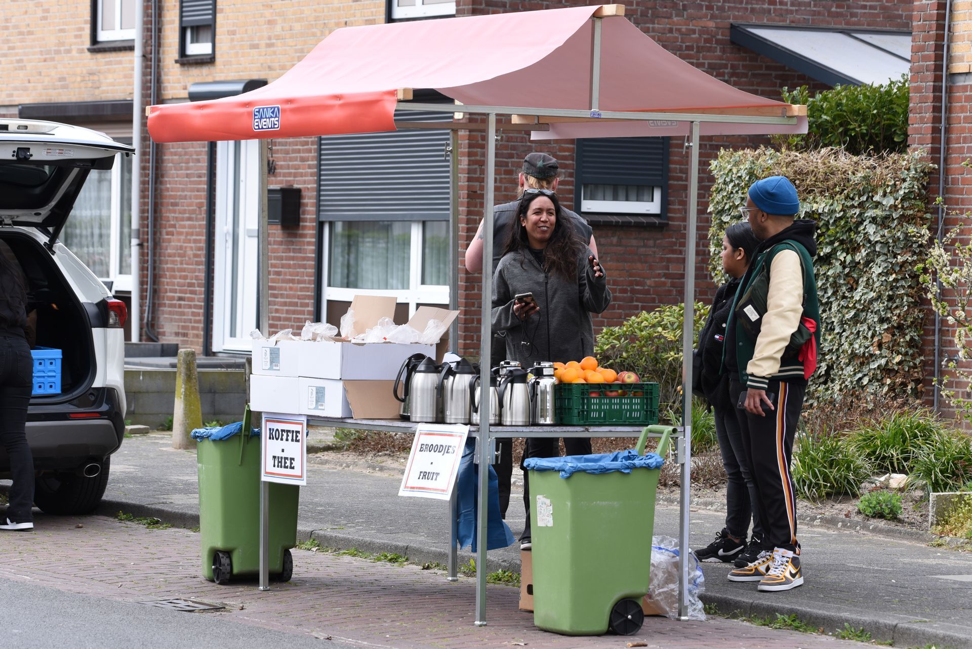 Een groep mensen staat rond een sapkraam aan de kant van de weg.