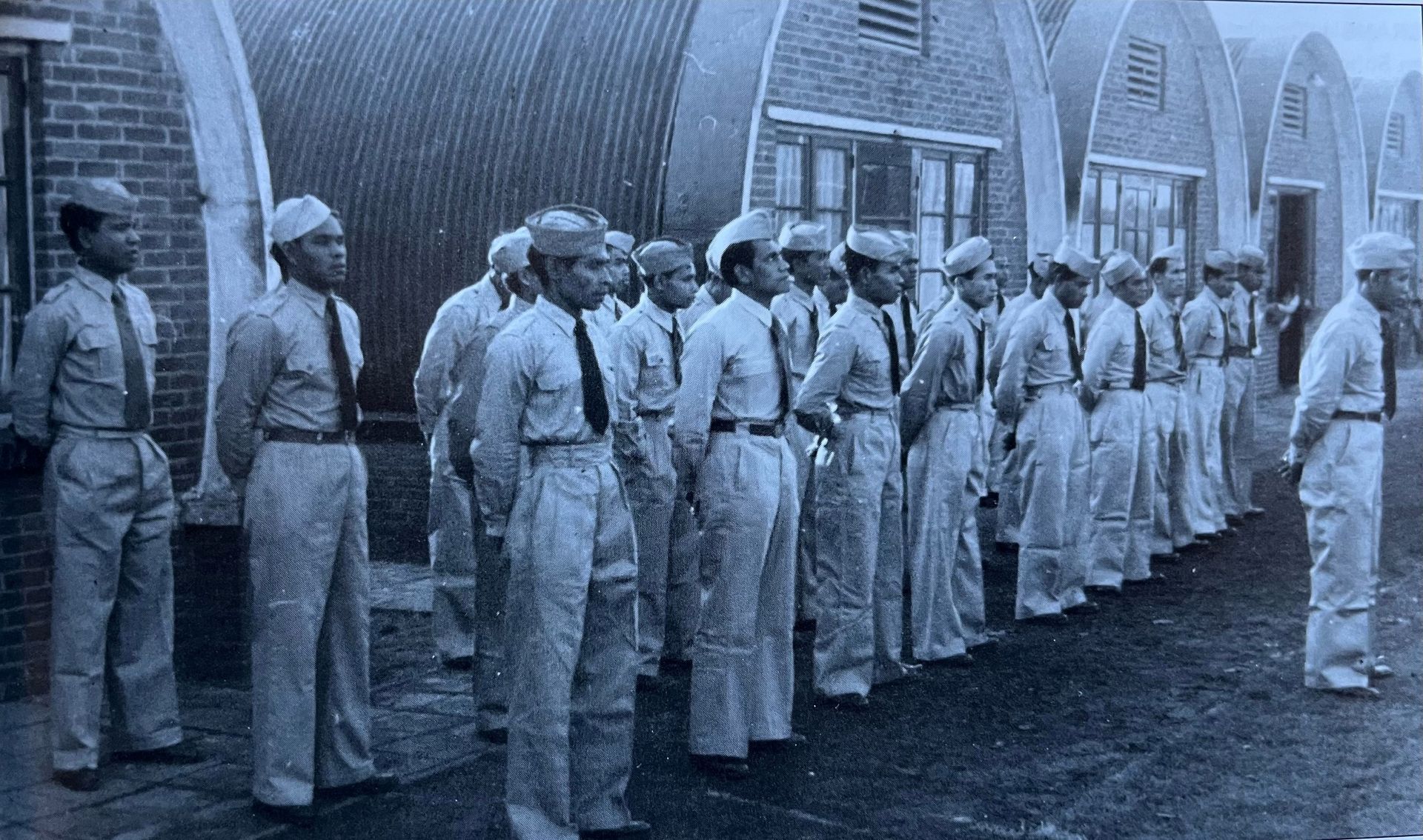 Een zwart-witfoto van een groep mannen in uniform die in een rij staan.