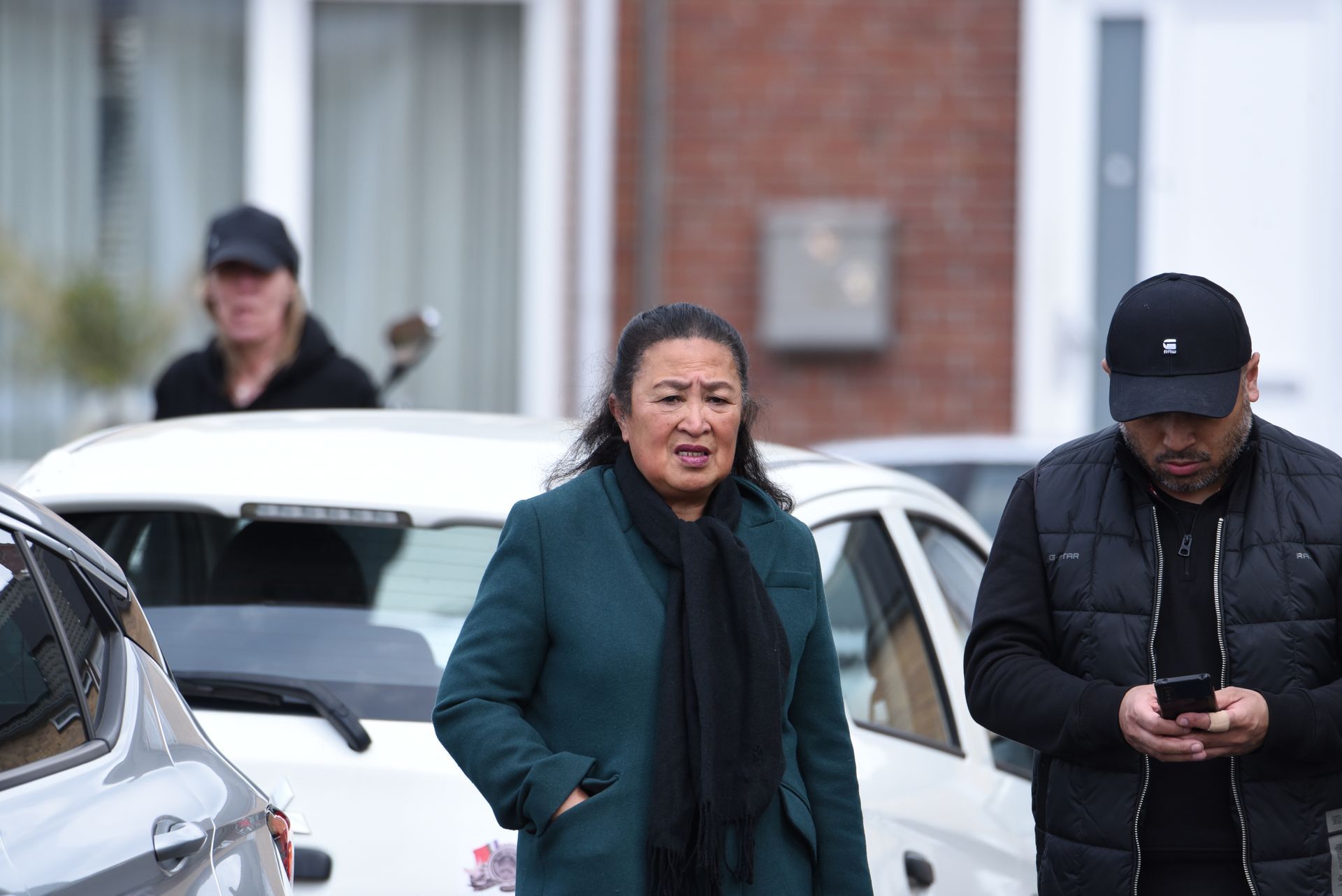 Een vrouw in een groene jas staat naast een man met een zwarte hoed.