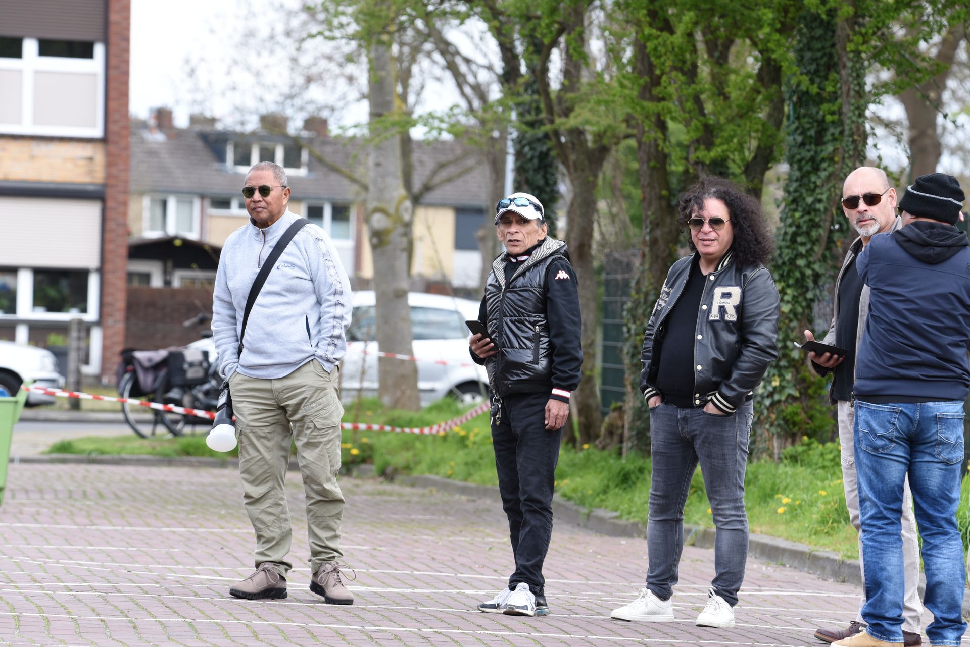 Een groep mannen staat naast elkaar op een trottoir.