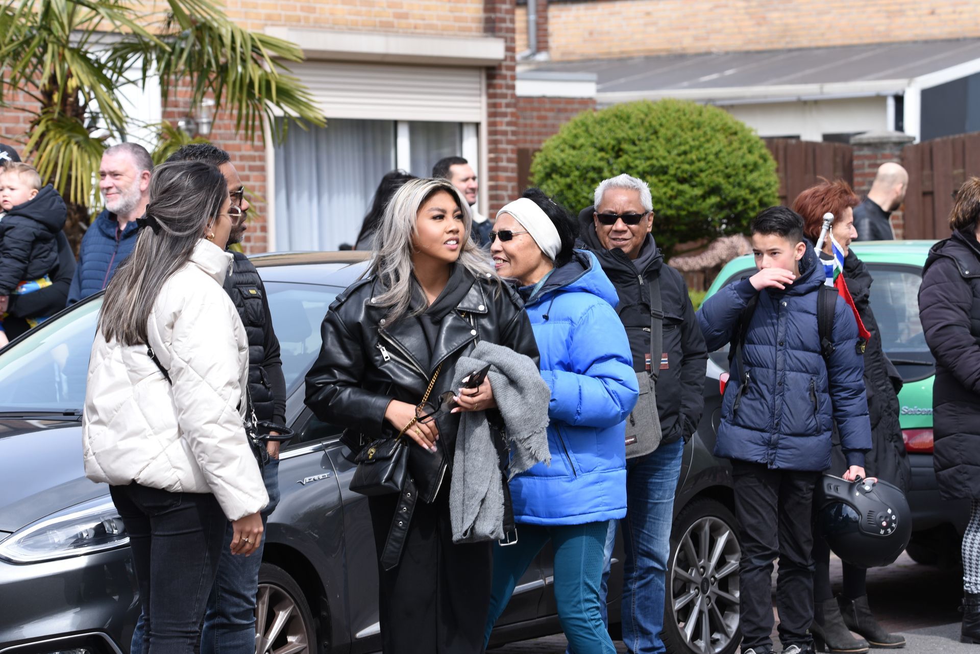 Een groep mensen staat voor een auto.