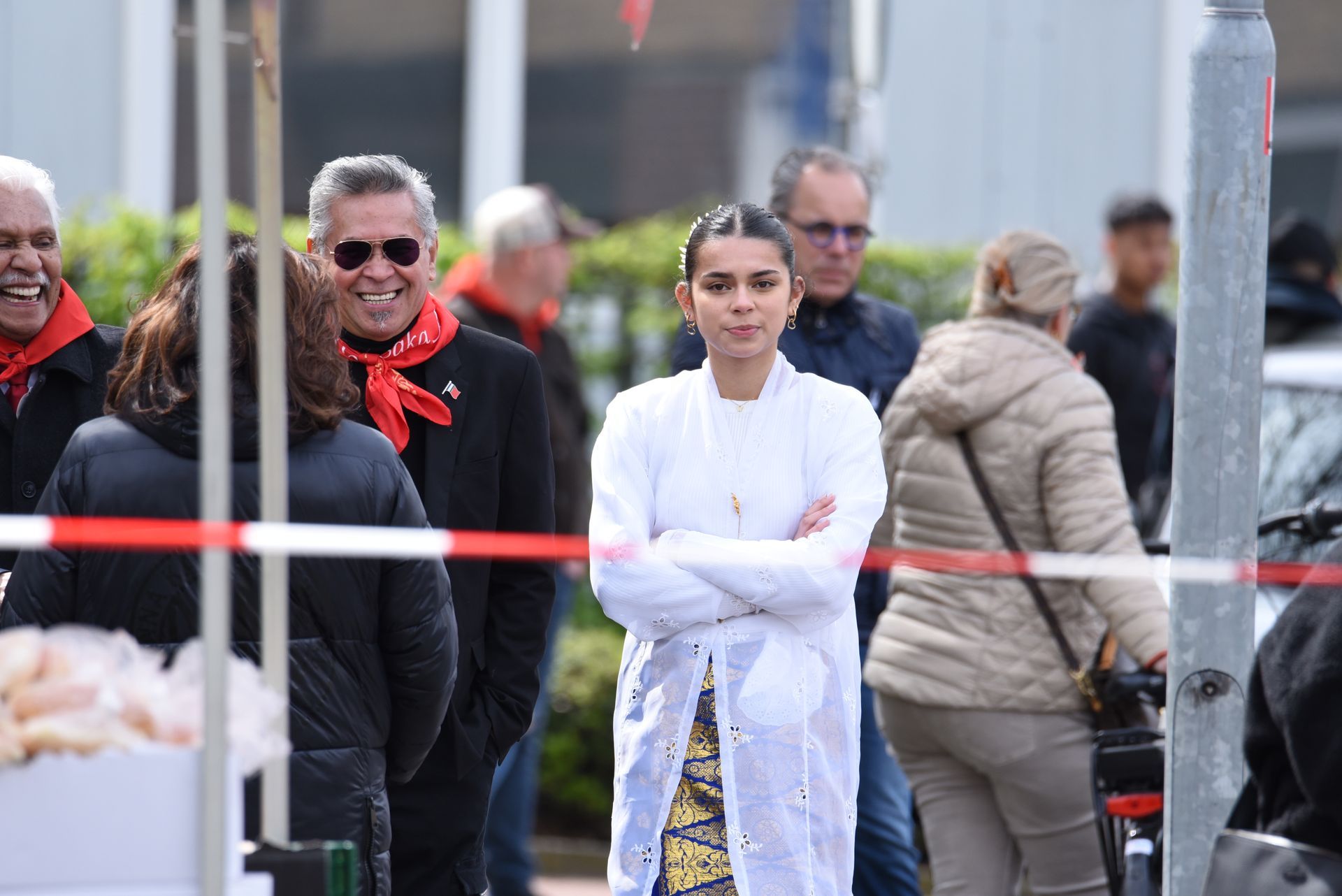 Een vrouw in een witte jas staat tussen een menigte mensen.