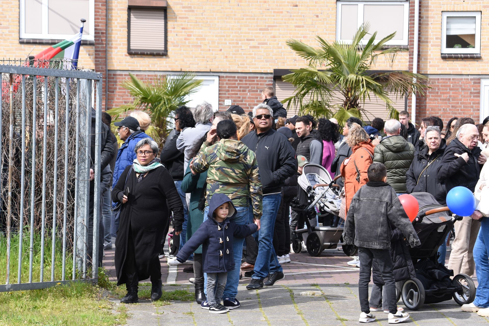 Een grote groep mensen staat buiten een gebouw.