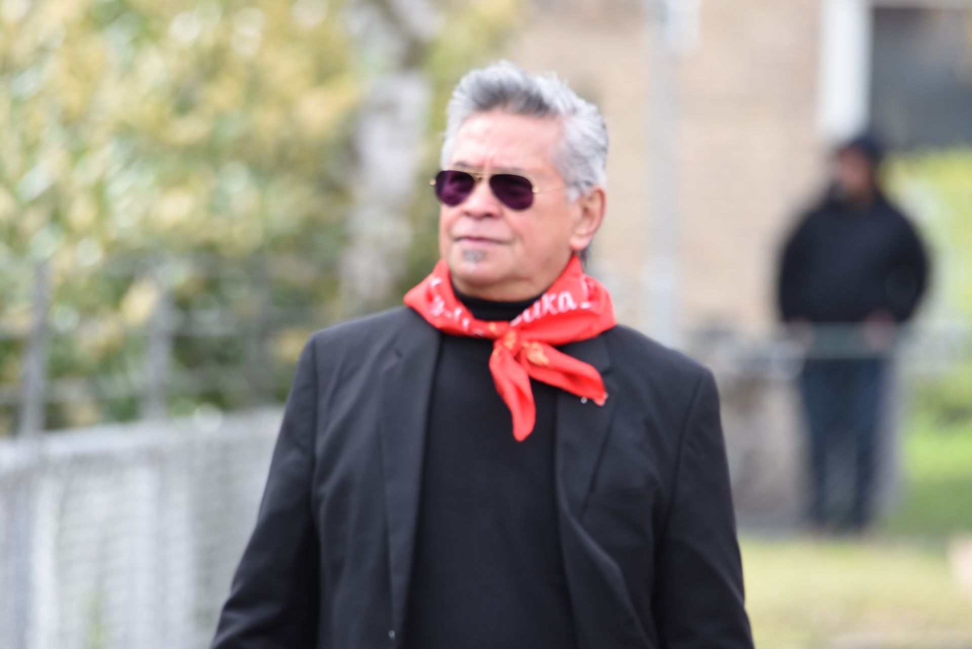 Een man met een zonnebril en een rode sjaal om zijn nek.