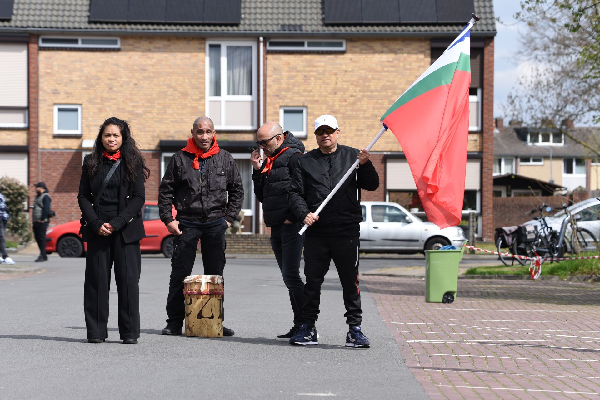 Een groep mensen die op de stoep staan ​​en een vlag vasthouden.