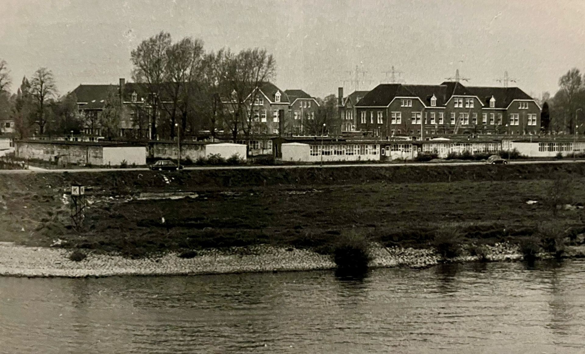 Een zwart-witfoto van een rivier met gebouwen op de achtergrond