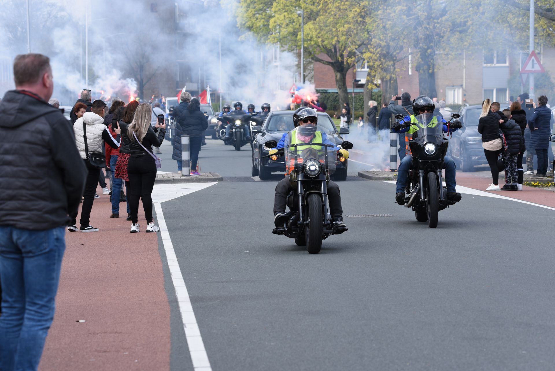 Een groep mensen rijdt op motorfietsen door een straat.