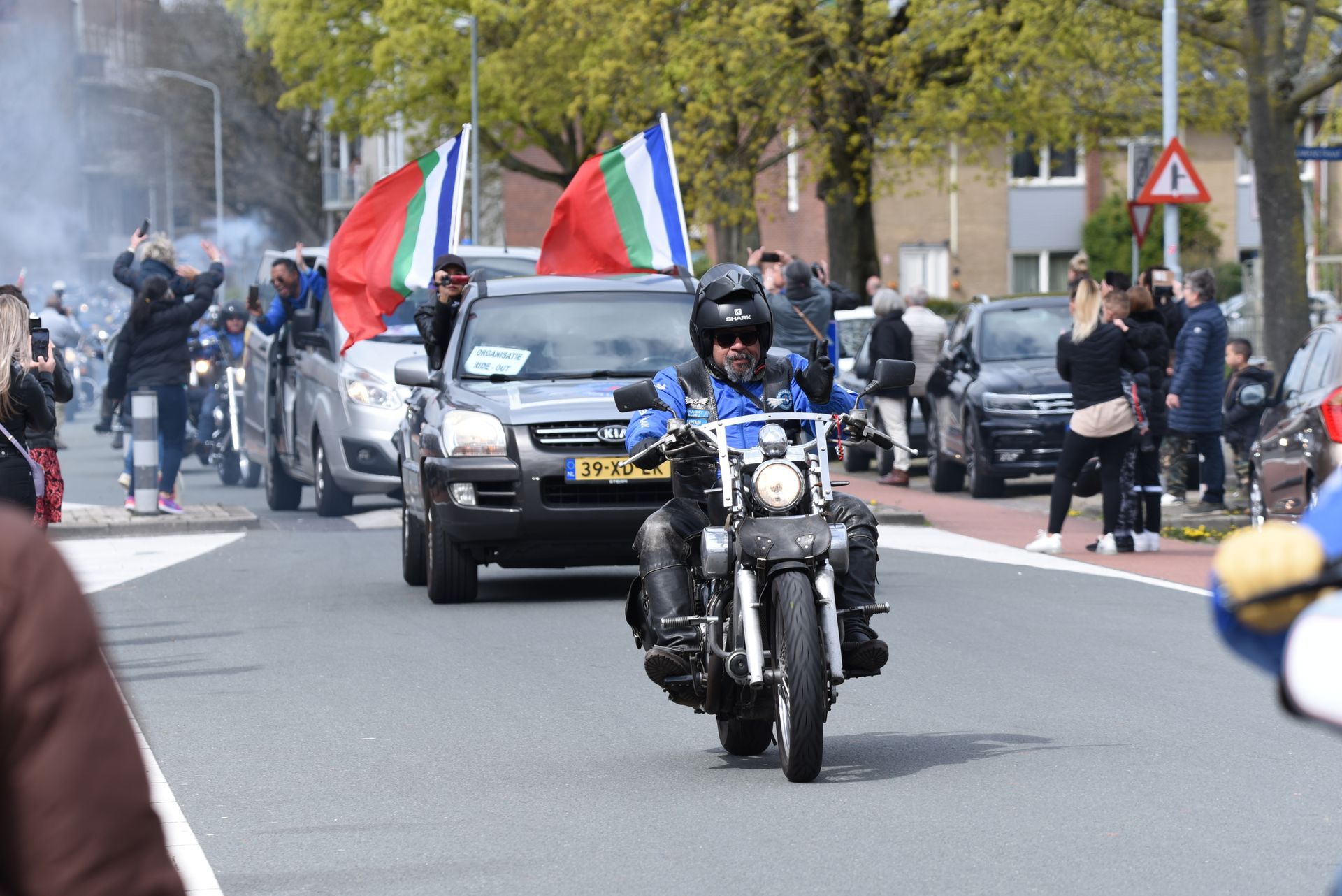 Een groep mensen rijdt op motorfietsen door een straat.