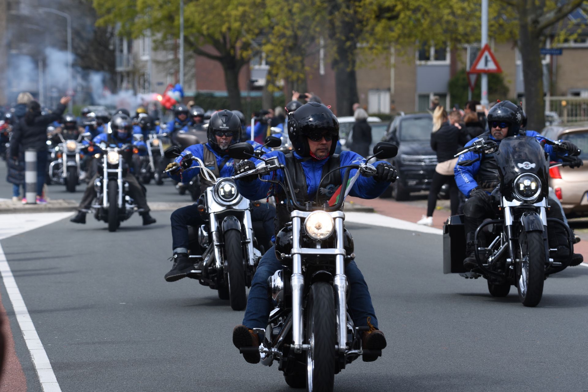Een groep mannen rijdt op motorfietsen door een straat.