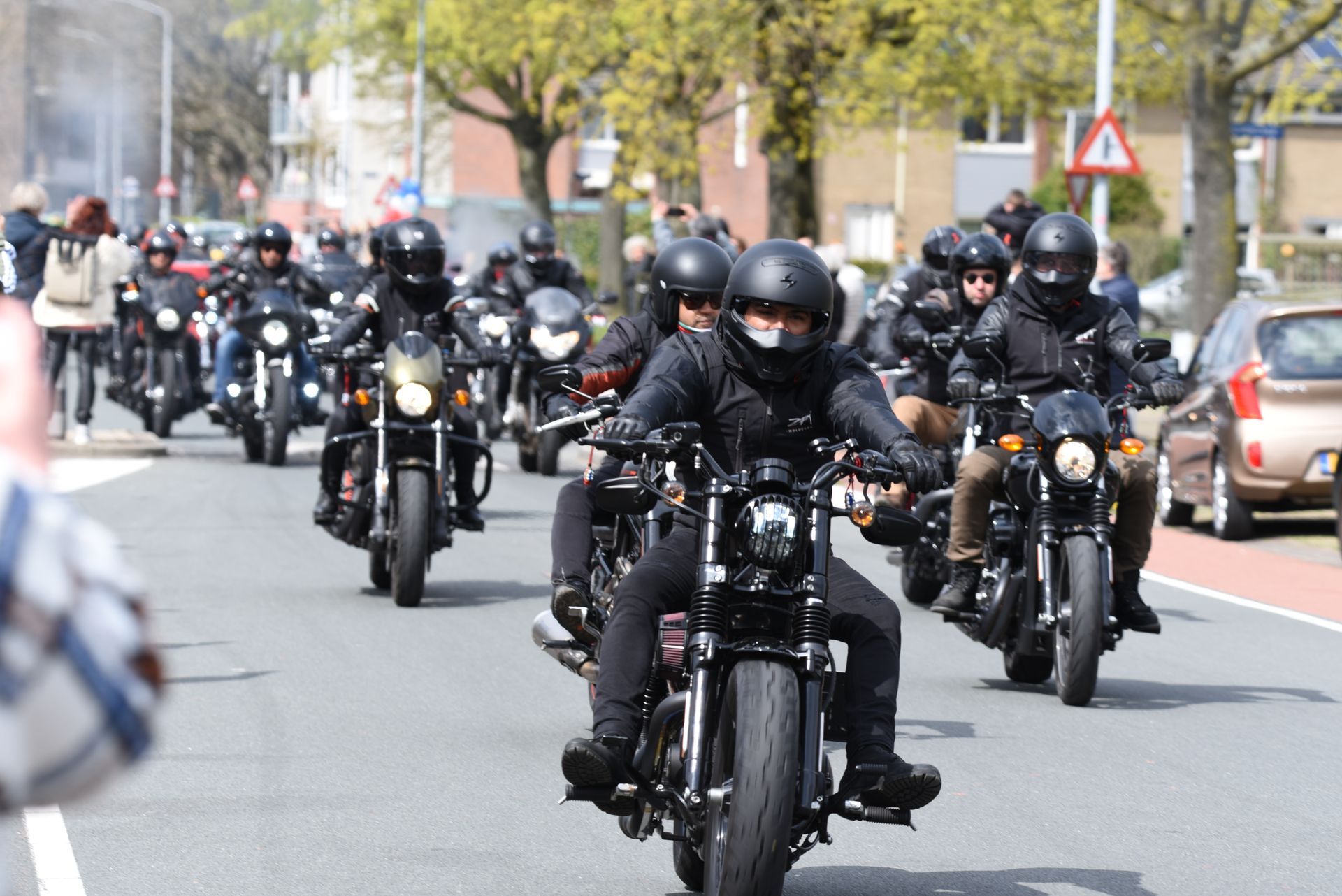 Een groep mensen rijdt op motorfietsen door een straat.