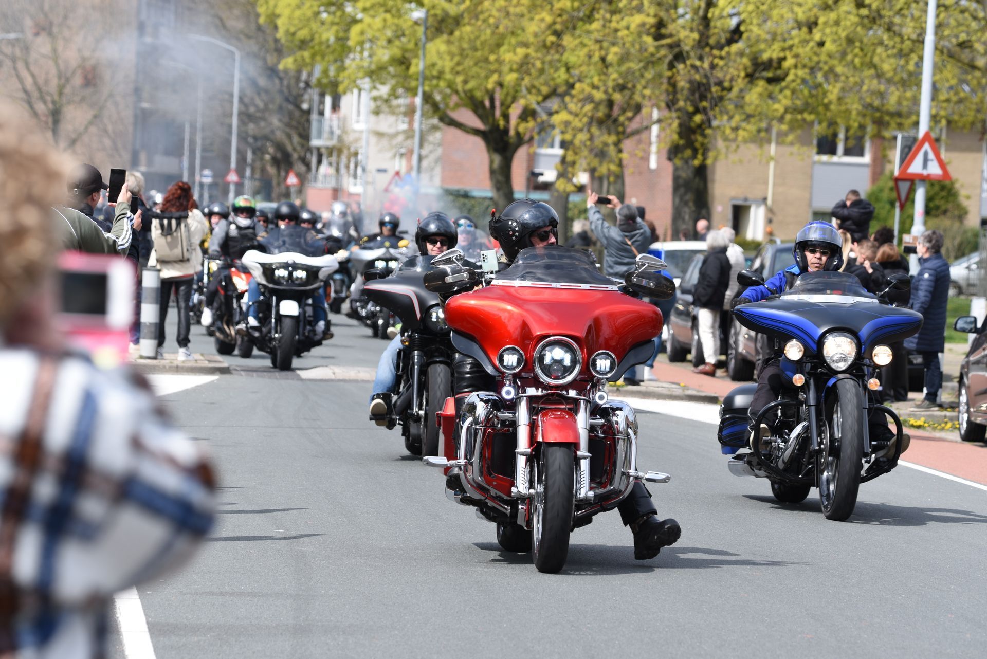 Een groep mensen rijdt op motorfietsen door een straat.
