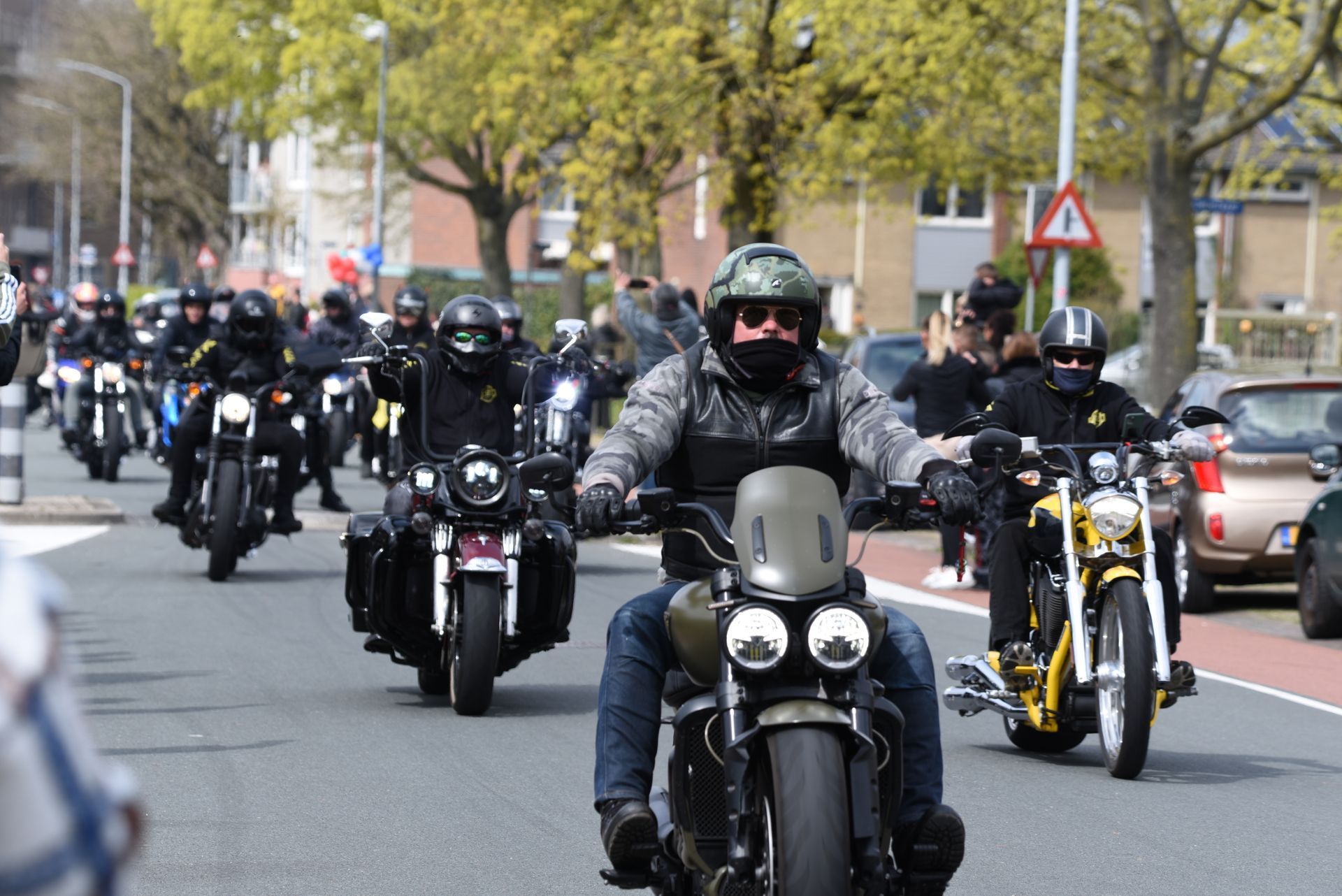 Een groep mensen rijdt op motorfietsen door een straat.