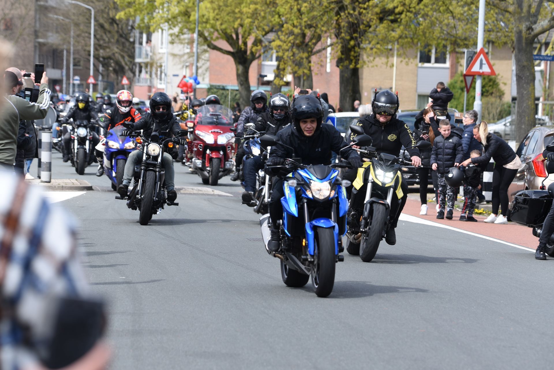Een groep mensen rijdt op motorfietsen door een straat