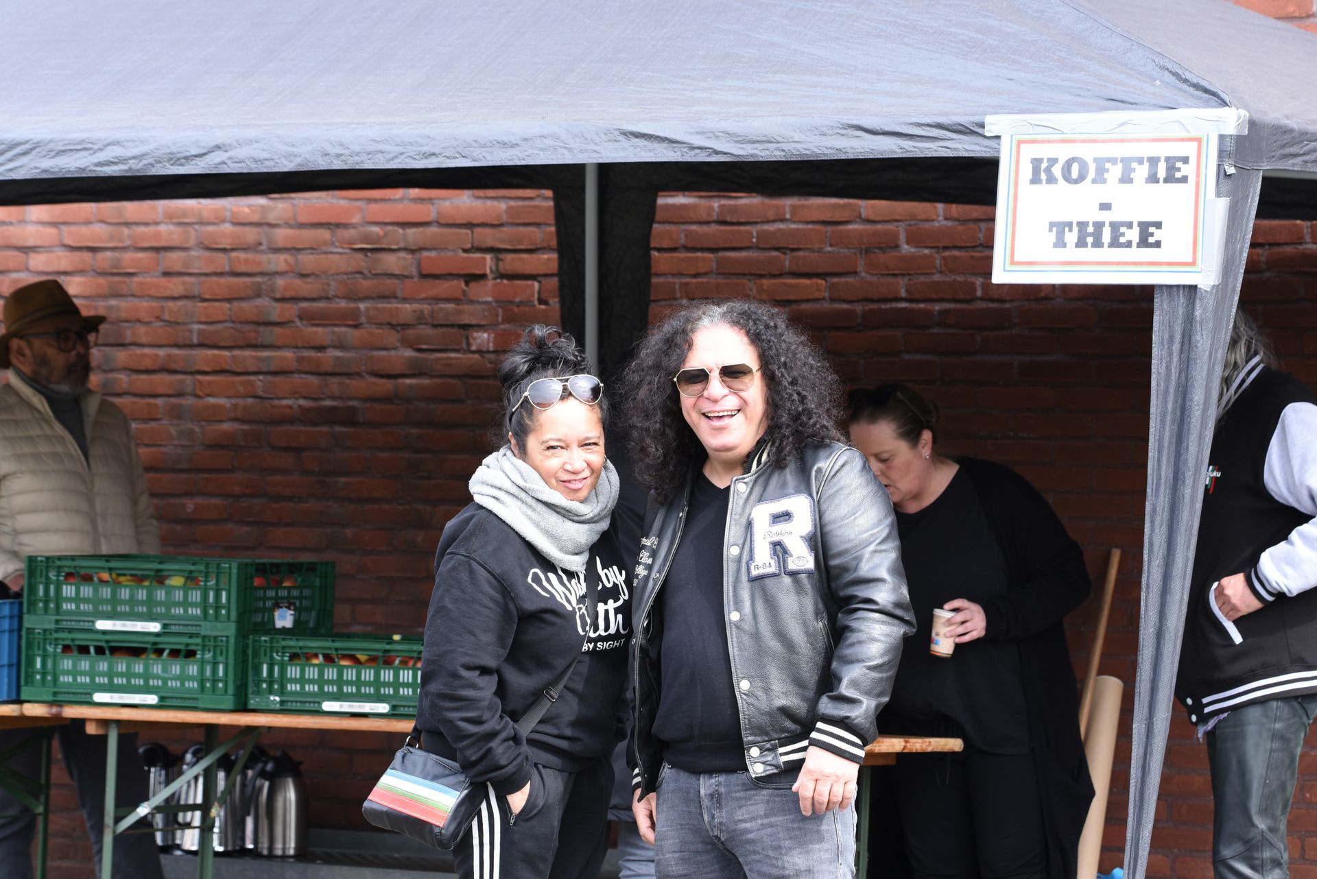 Onder een tent staan ​​een man en een vrouw met een bordje koffie thee