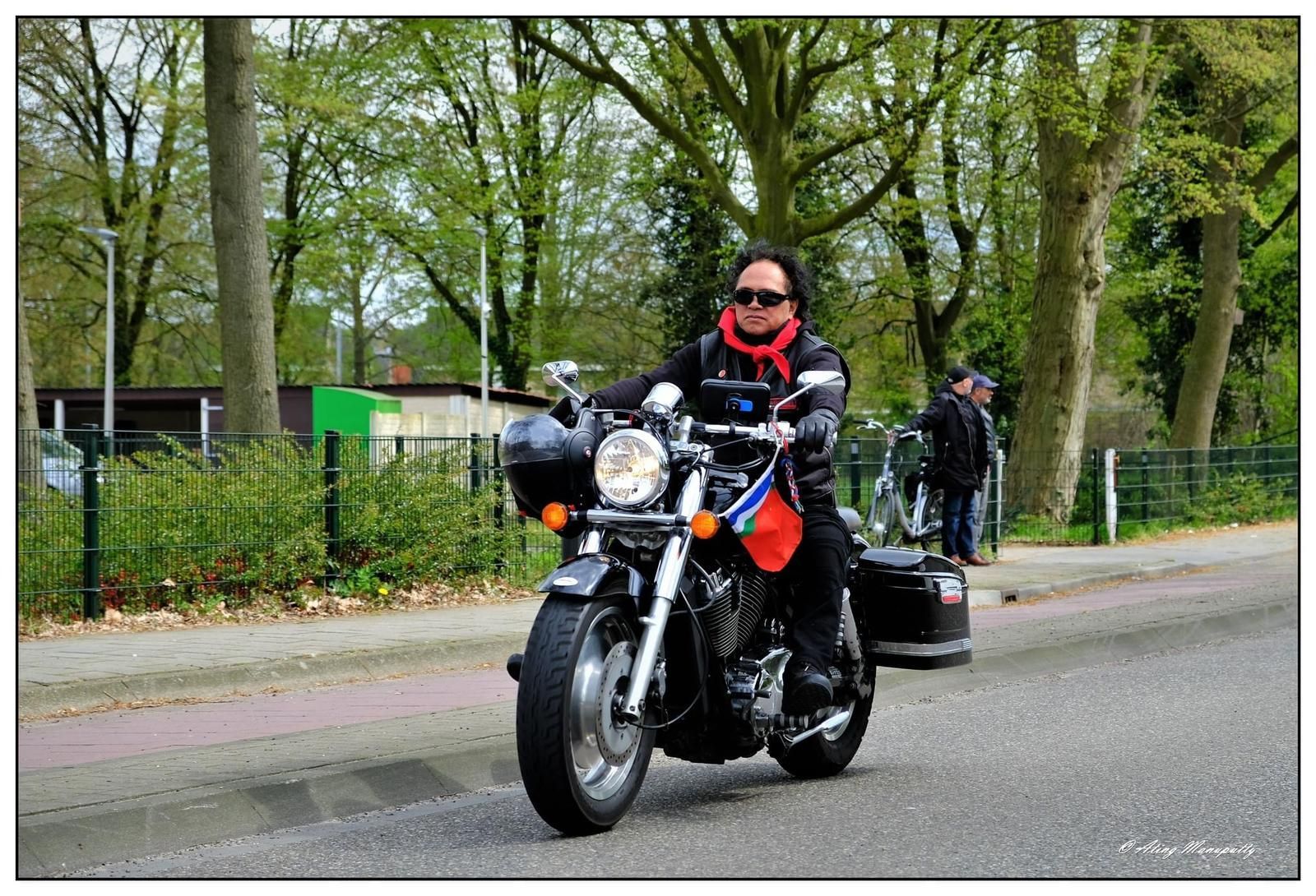 Een man rijdt op een motorfiets door een straat