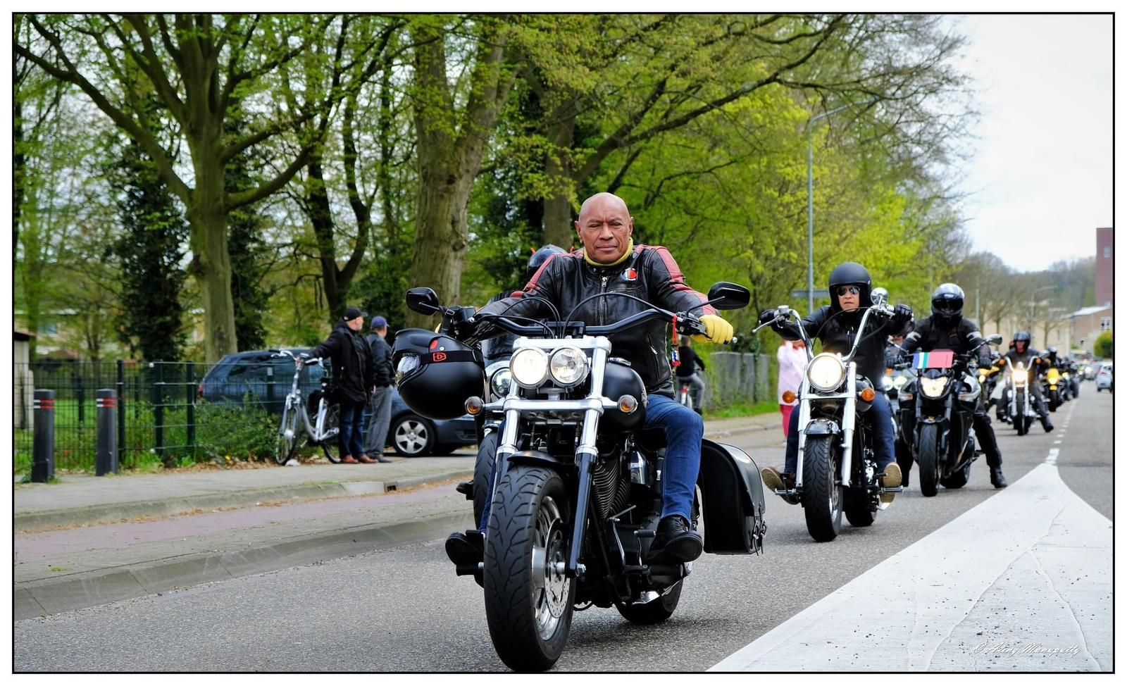 Een groep mensen die op motorfietsen door een straat rijden