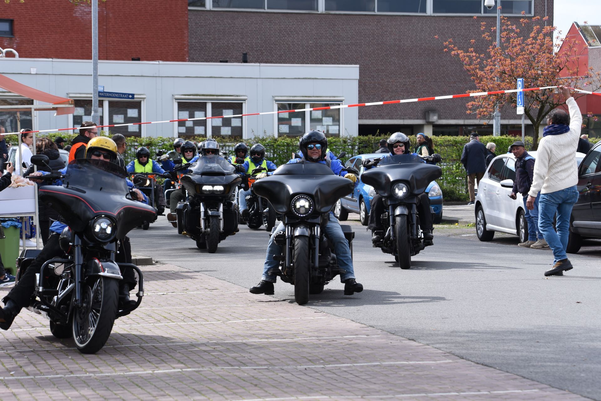 Een groep mensen rijdt op motorfietsen door een straat.