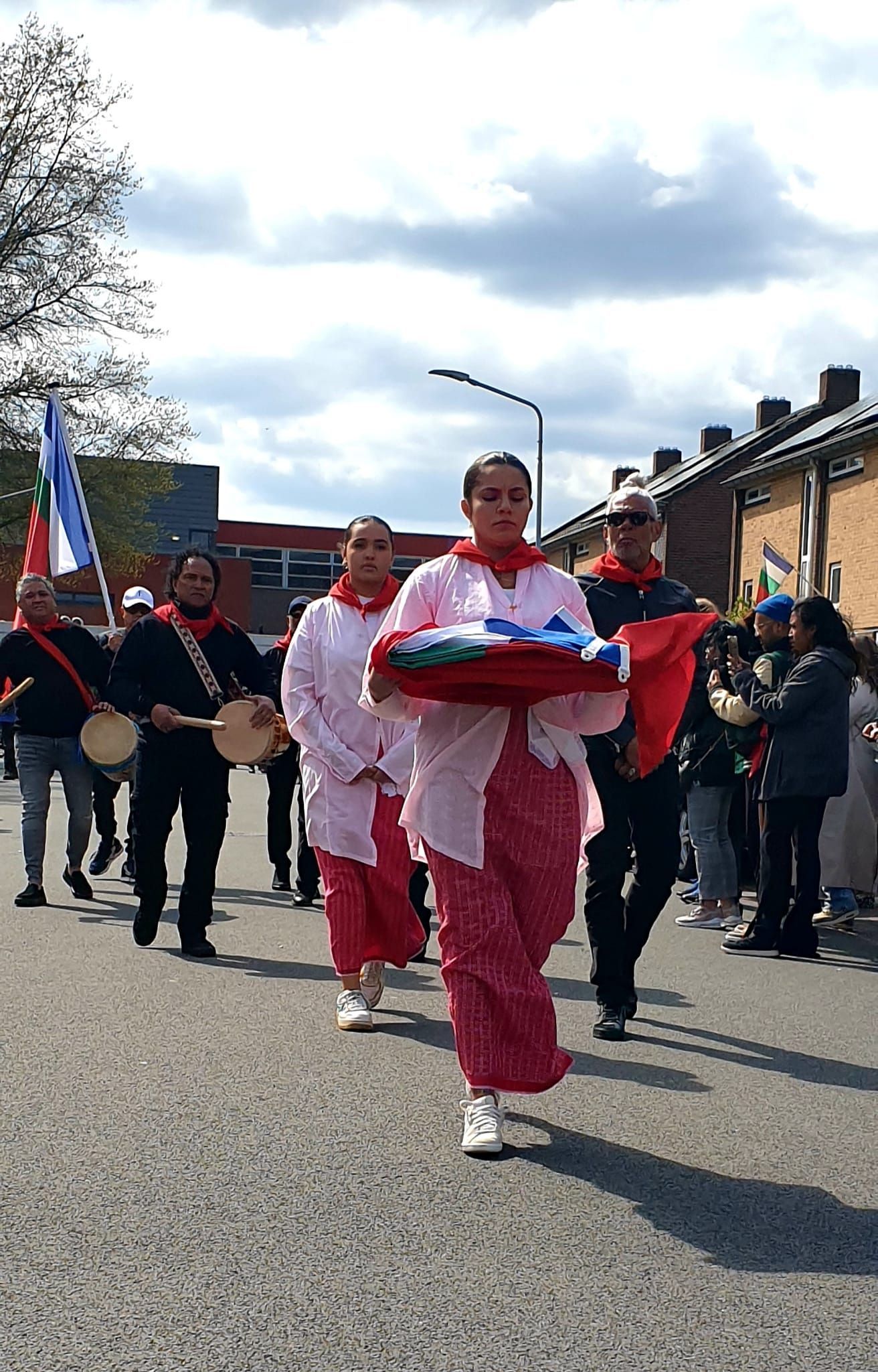 Een groep mensen marcheert in een parade door de straat.