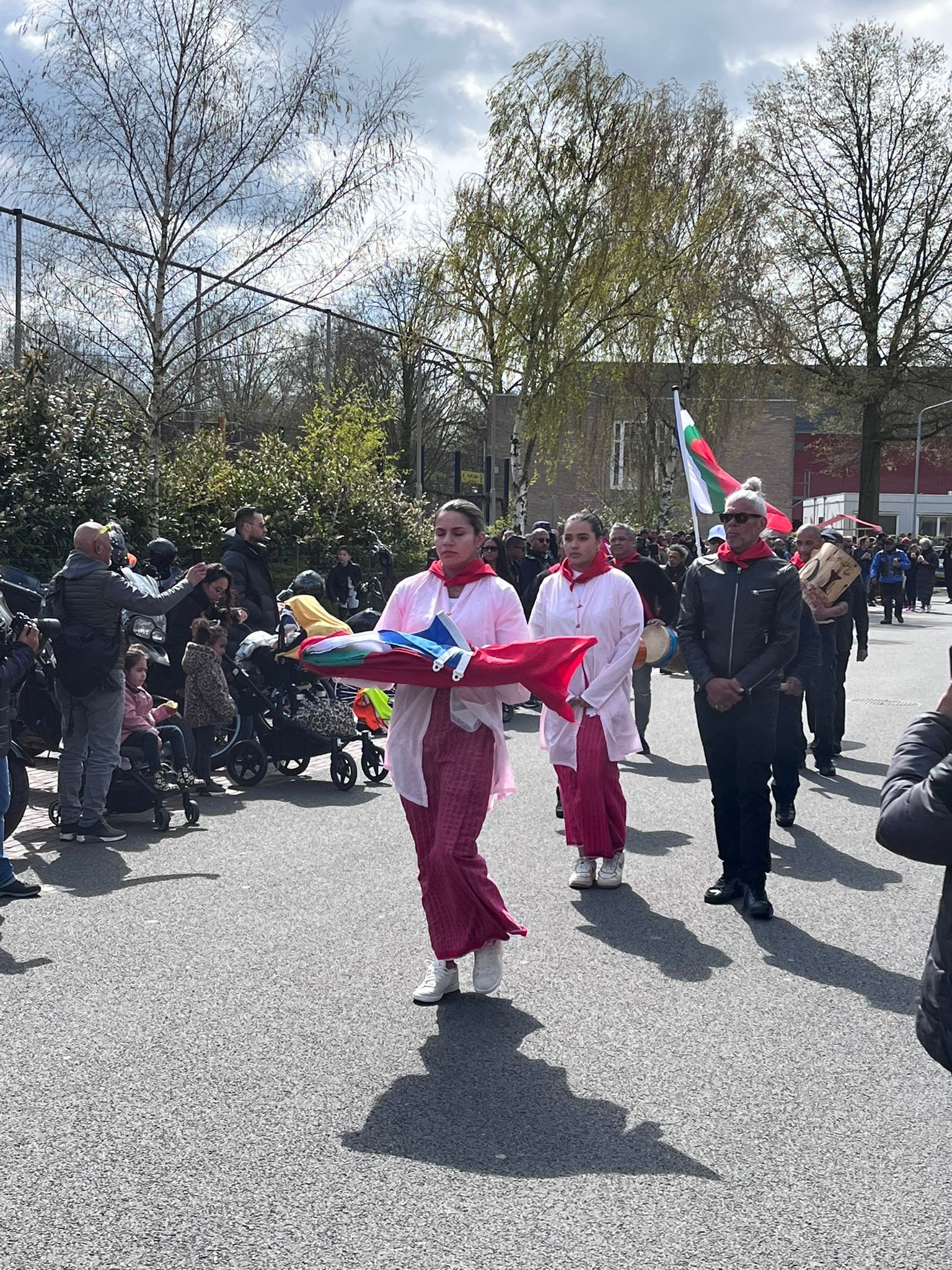 Een groep mensen loopt in een parade door de straat.