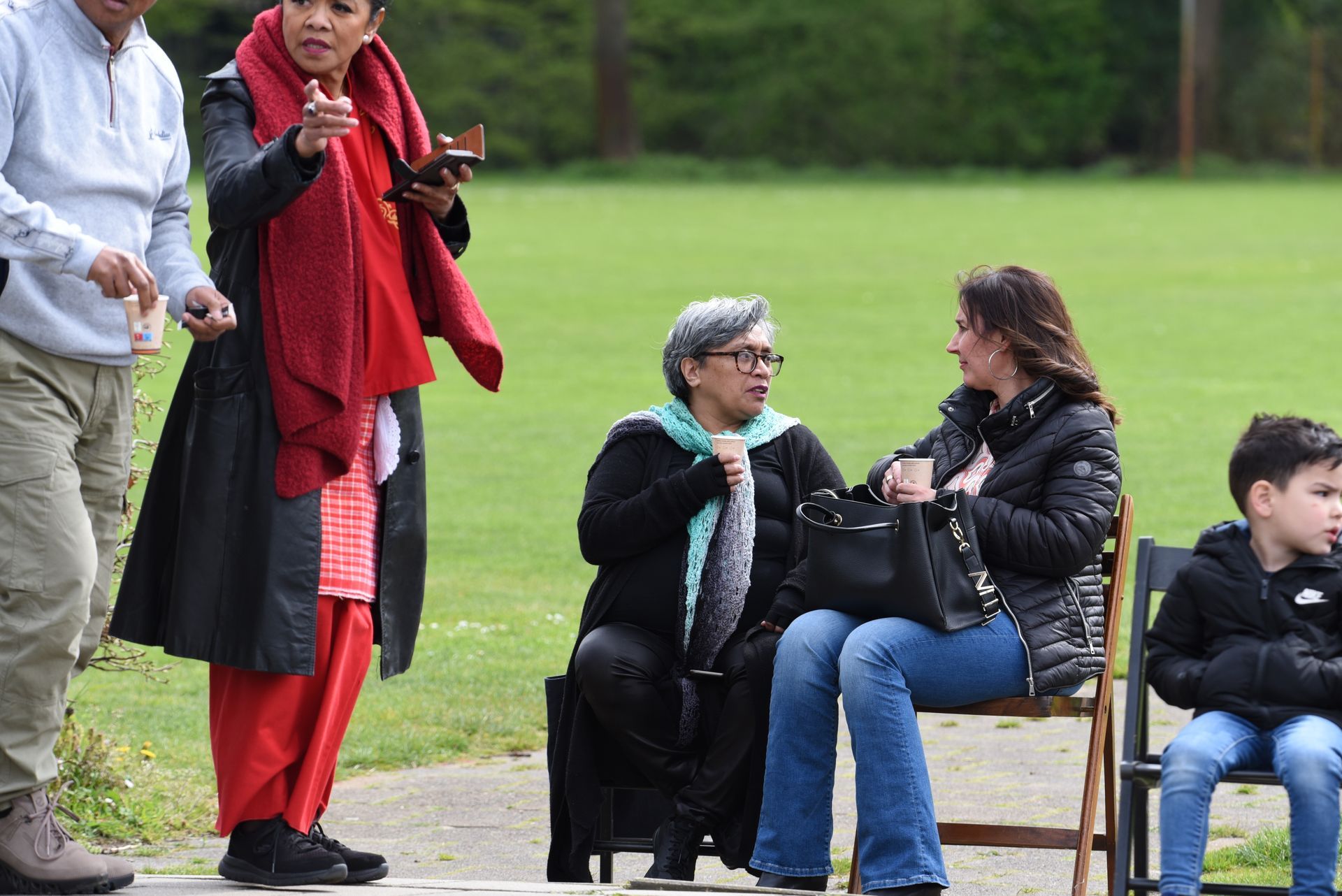 Een groep mensen staat en zit in een park.