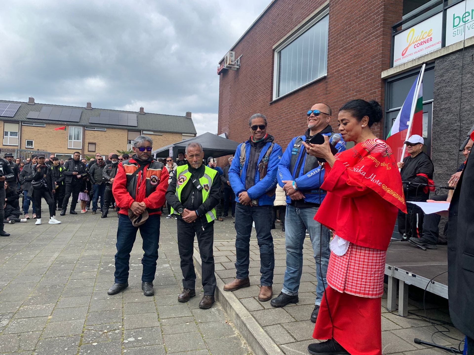 Een groep mensen die op de stoep voor een gebouw staan.