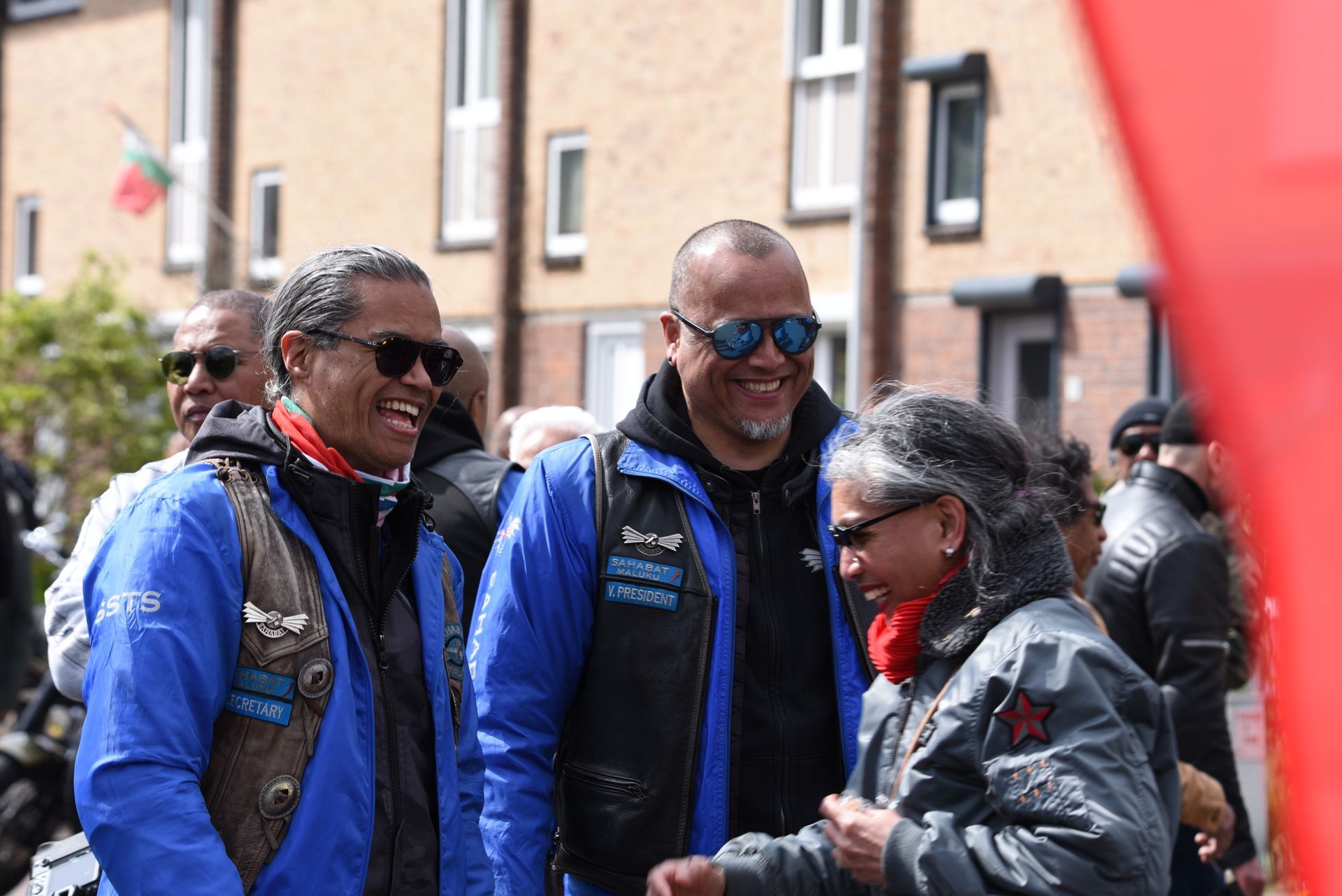 Een groep mensen staat naast elkaar voor een gebouw.