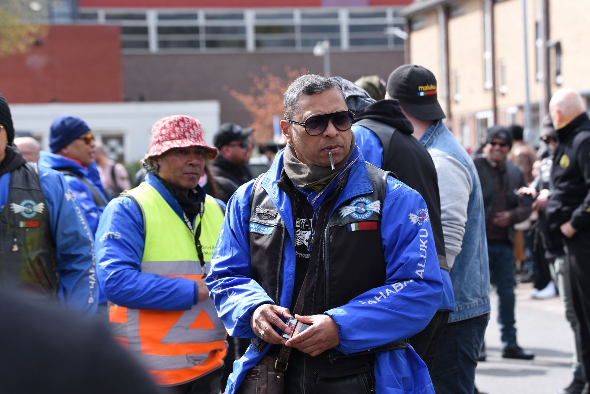 Een man in een blauw jasje staat tussen een menigte mensen.