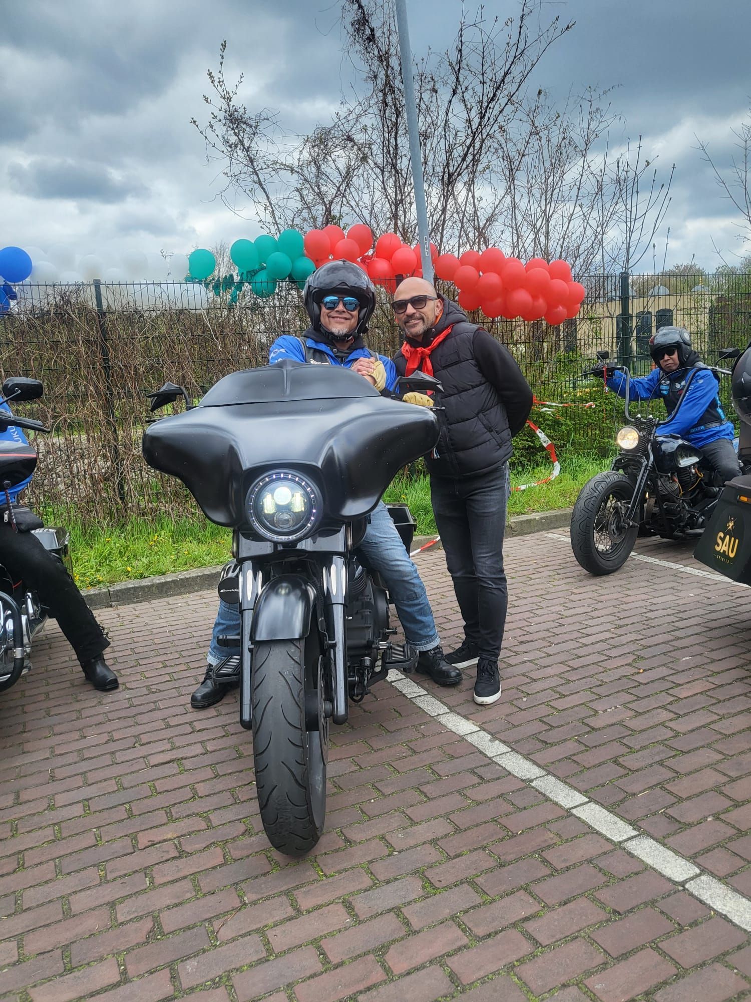 Twee mannen staan ​​naast een motorfiets op een parkeerplaats.
