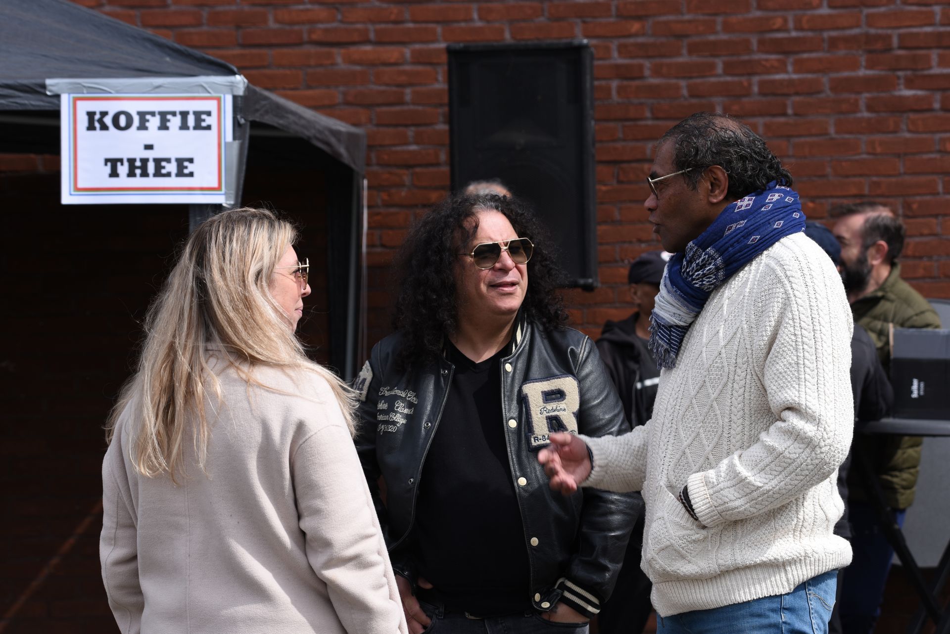 Een groep mensen staat voor een bord met de tekst koffie thee.
