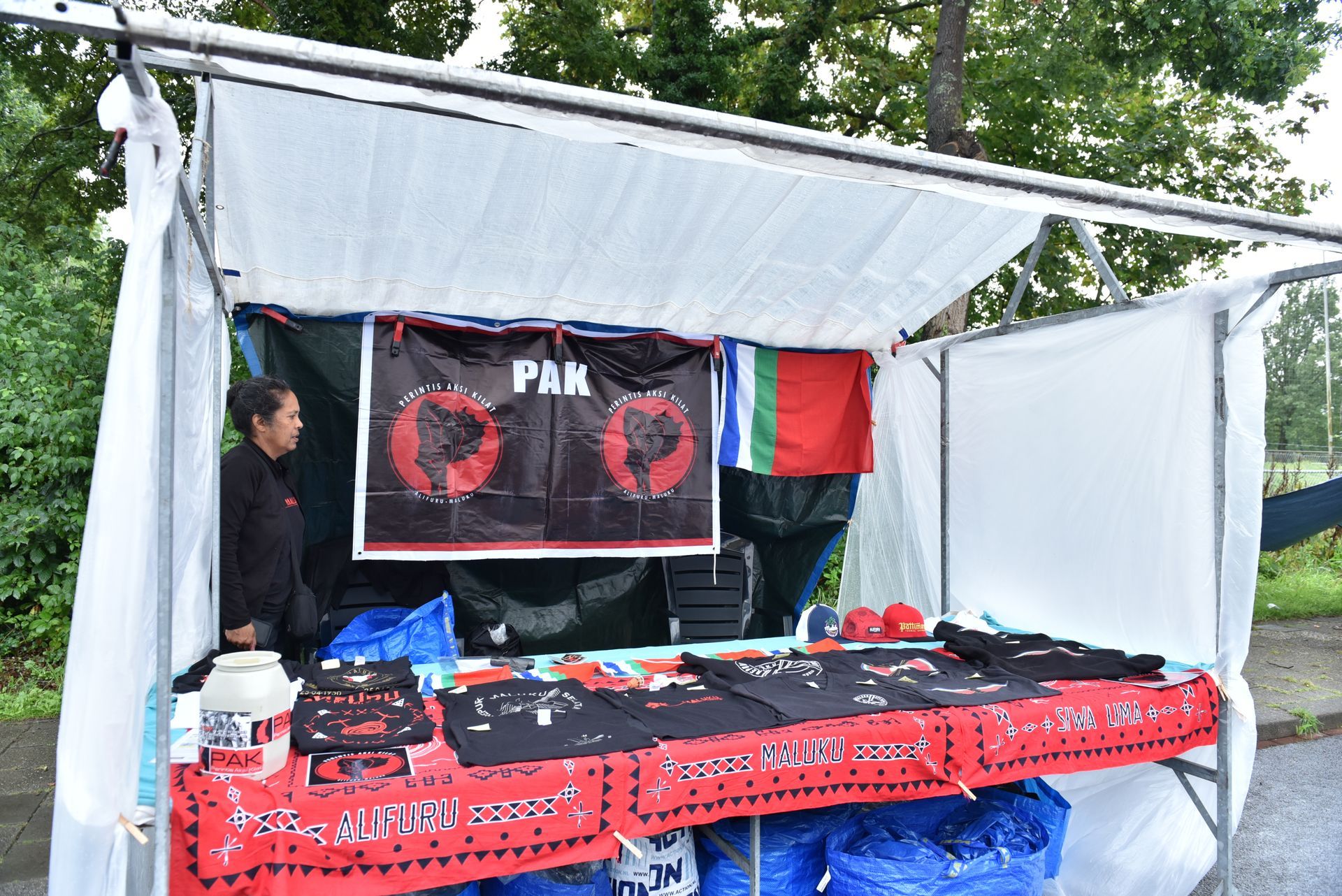 Een man staat achter een tafel met een bordje waarop 'pak' staat