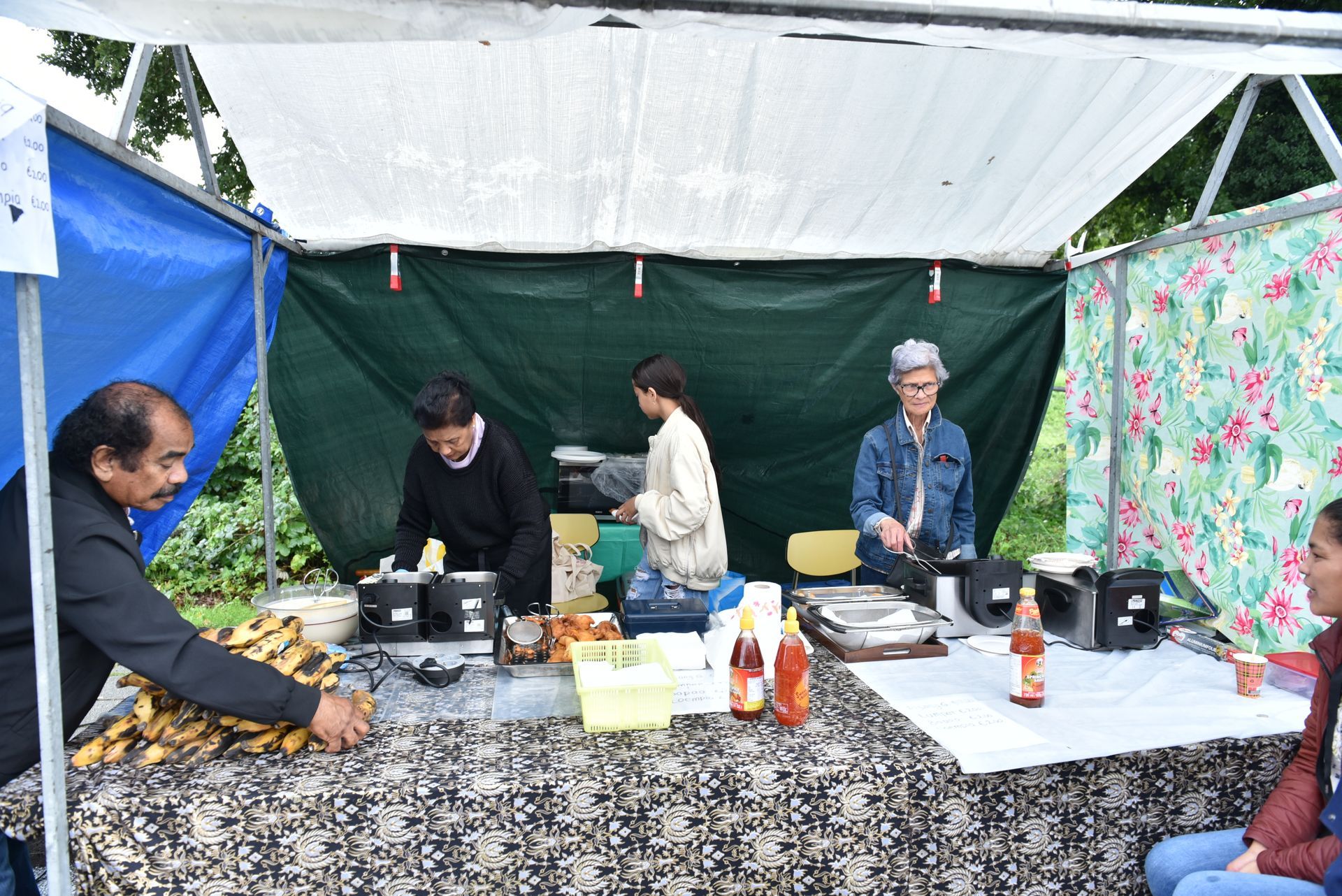 Een groep mensen staat rond een tafel onder een tent.