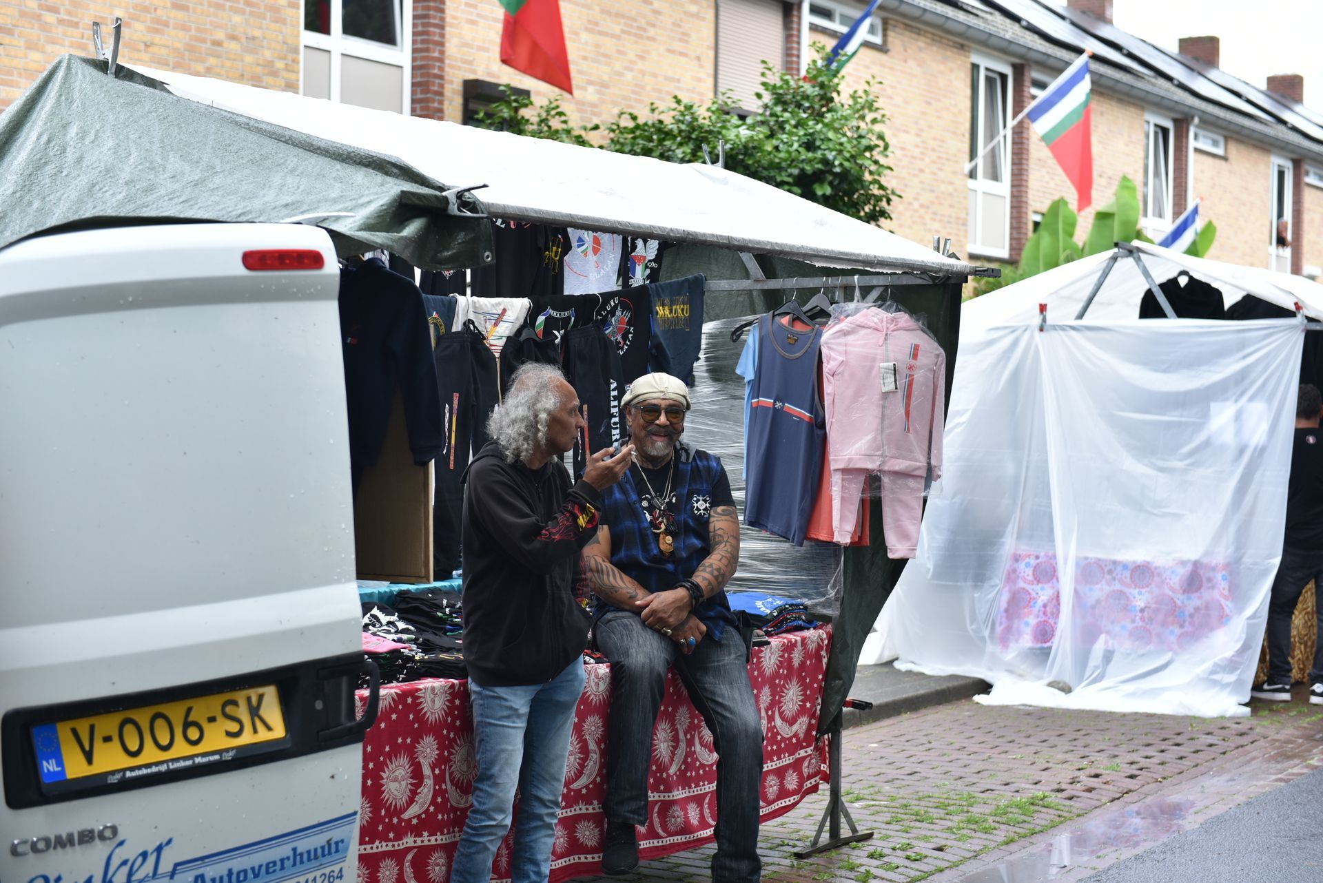 Twee mannen zitten voor een tent op een markt.