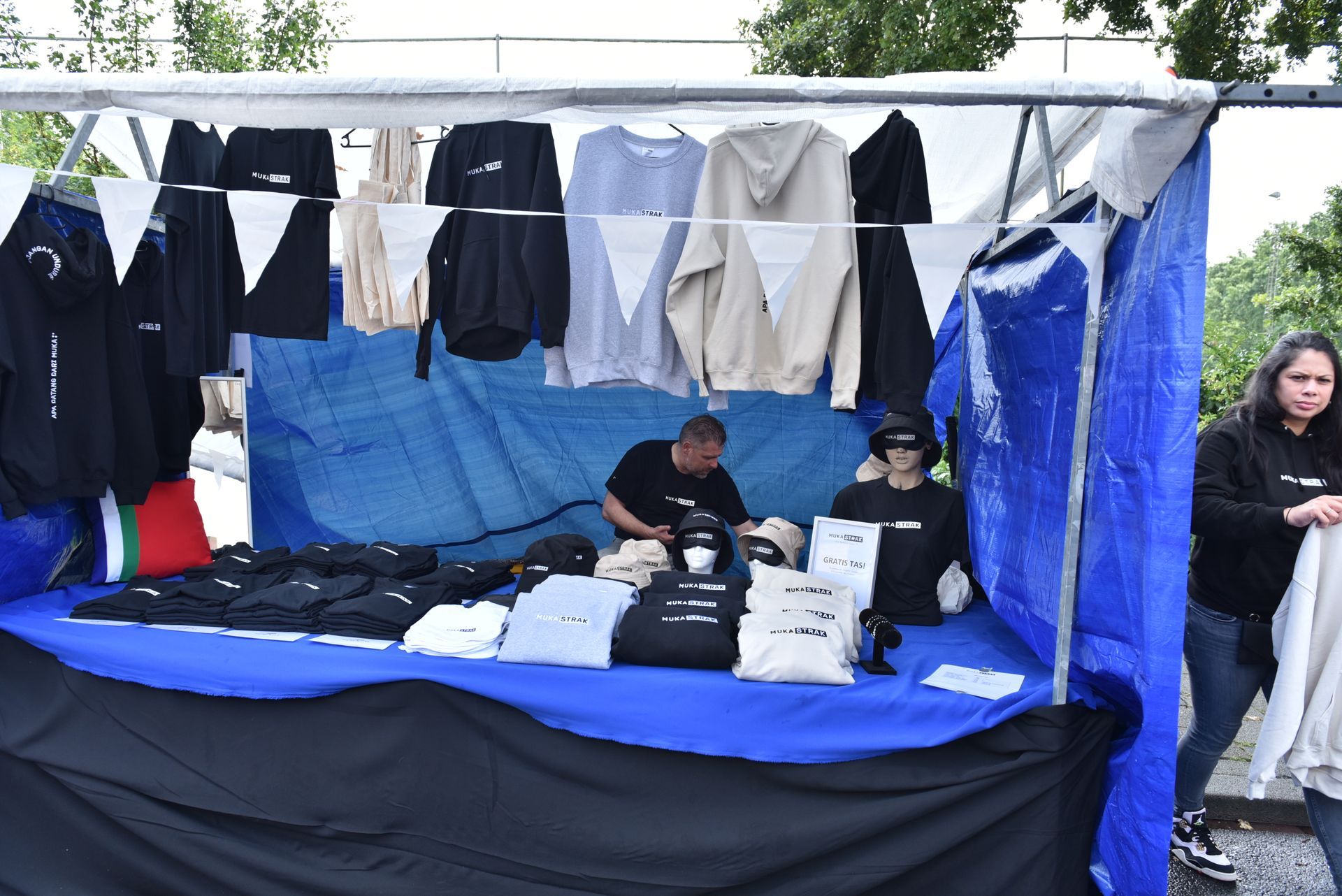 Een man en een vrouw zitten aan een tafel en verkopen overhemden.