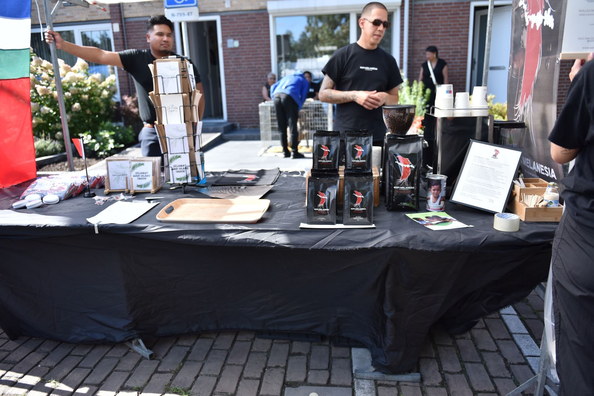 Een groep mensen staat rond een tafel met dozen koffie erop.