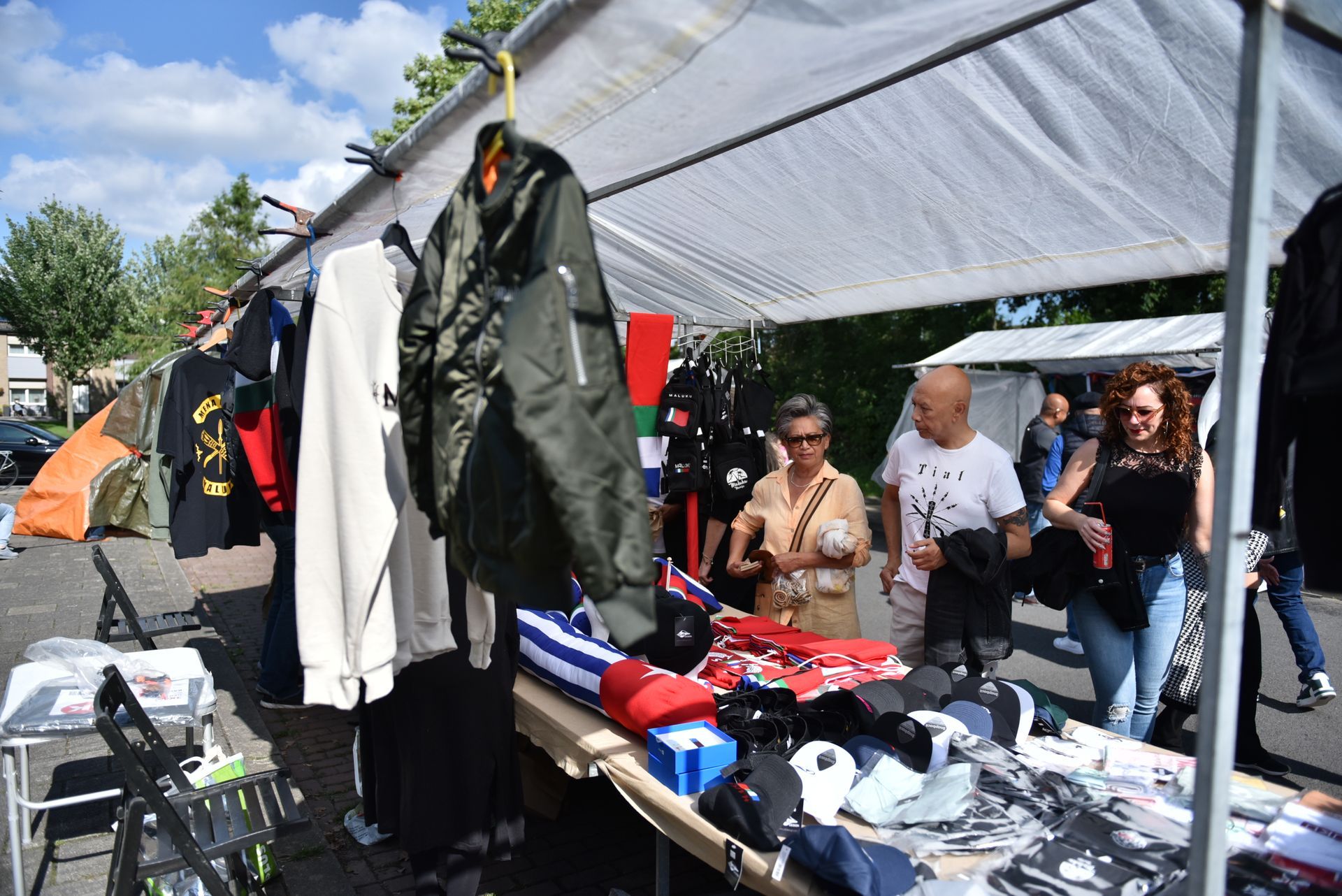 Een groep mensen staat rond een tafel op een rommelmarkt.