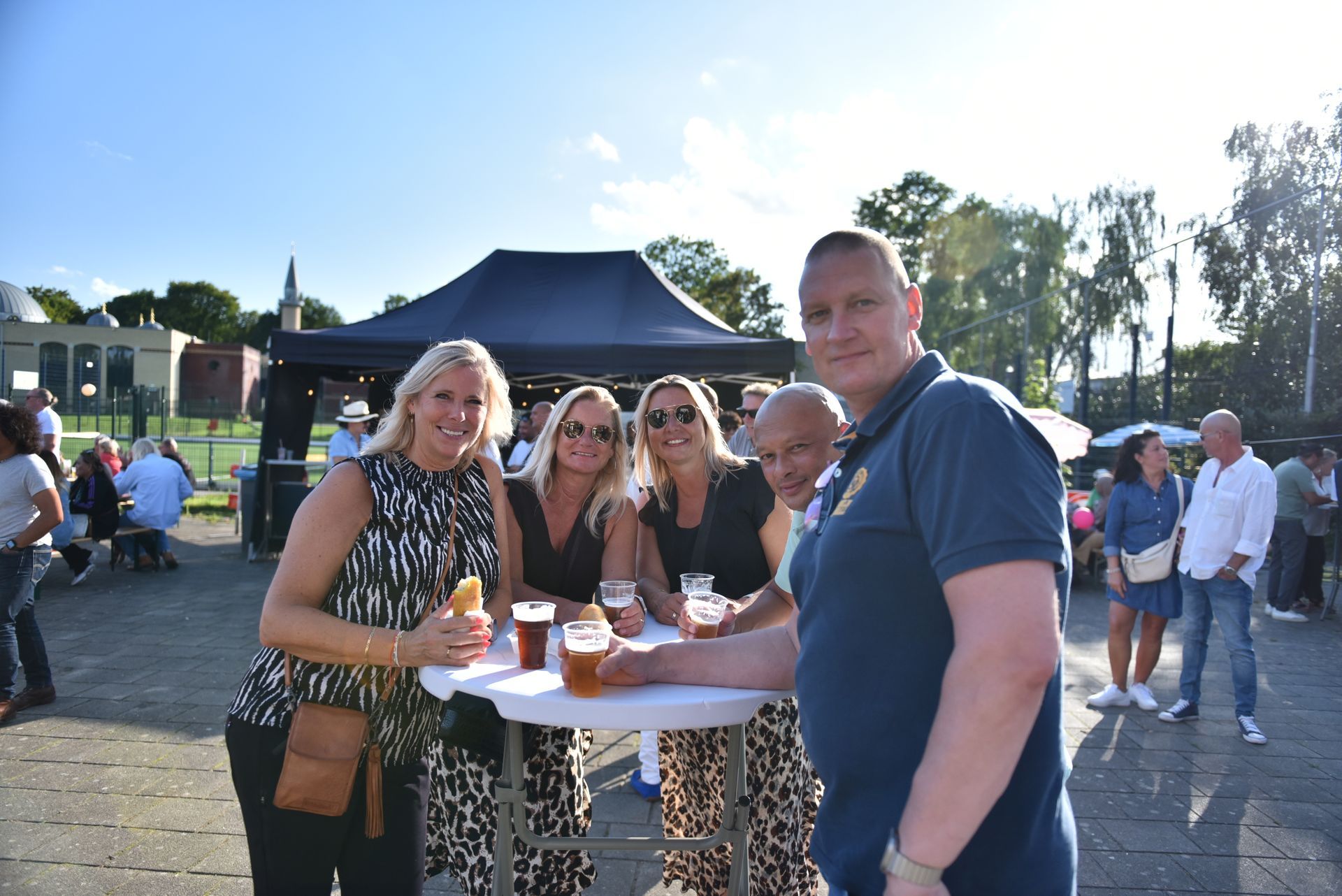 Een groep mensen staat rond een tafel met drankjes.