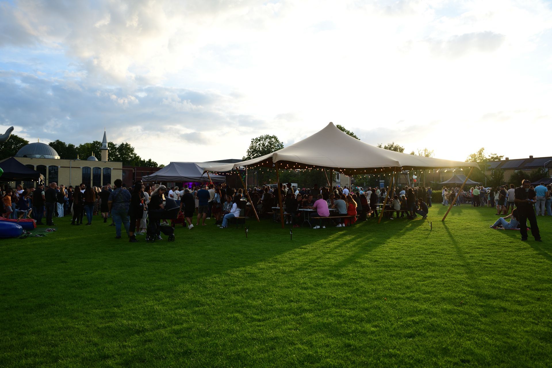 Een groep mensen zit onder een tent in een veld.