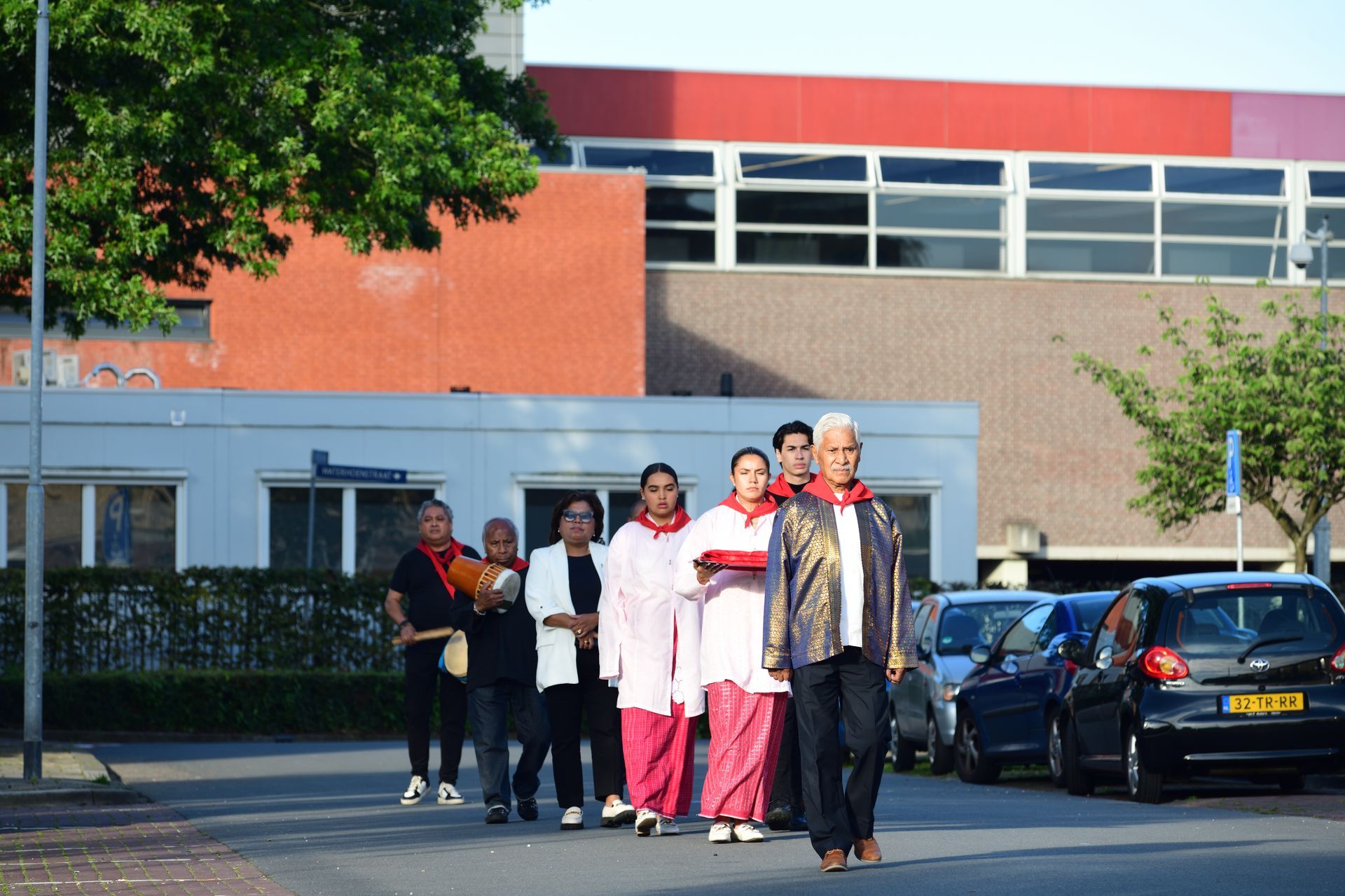 Een groep mensen loopt door de straat voor een gebouw.