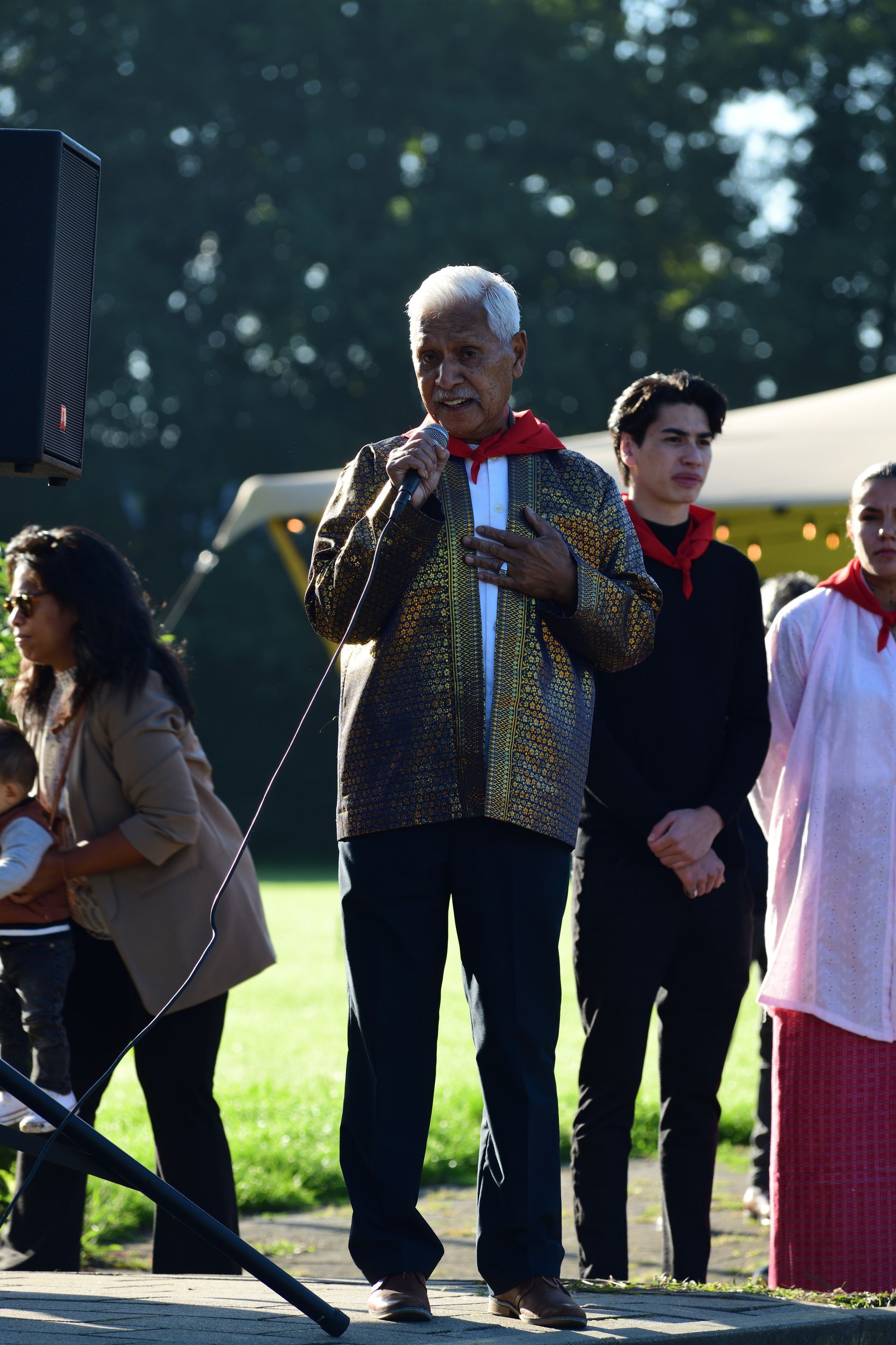 Een man spreekt in een microfoon voor een groep mensen.