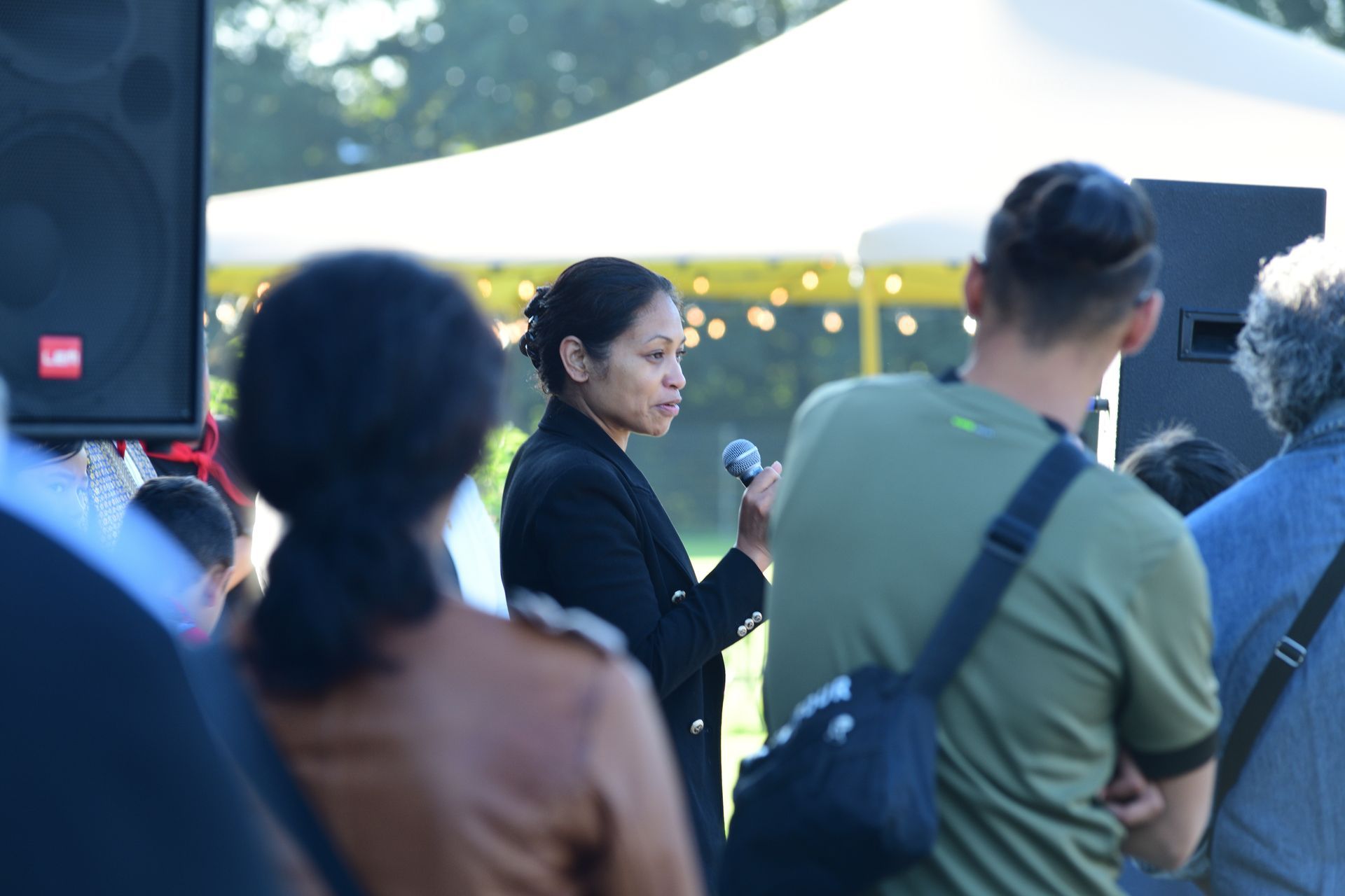 Een vrouw houdt een microfoon vast voor een menigte mensen.
