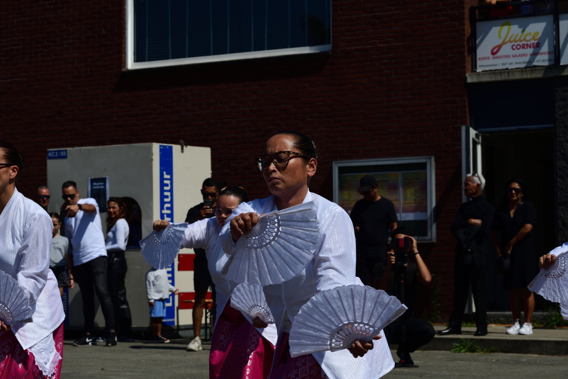 Een groep mensen danst voor een gebouw waar 'huur' op staat