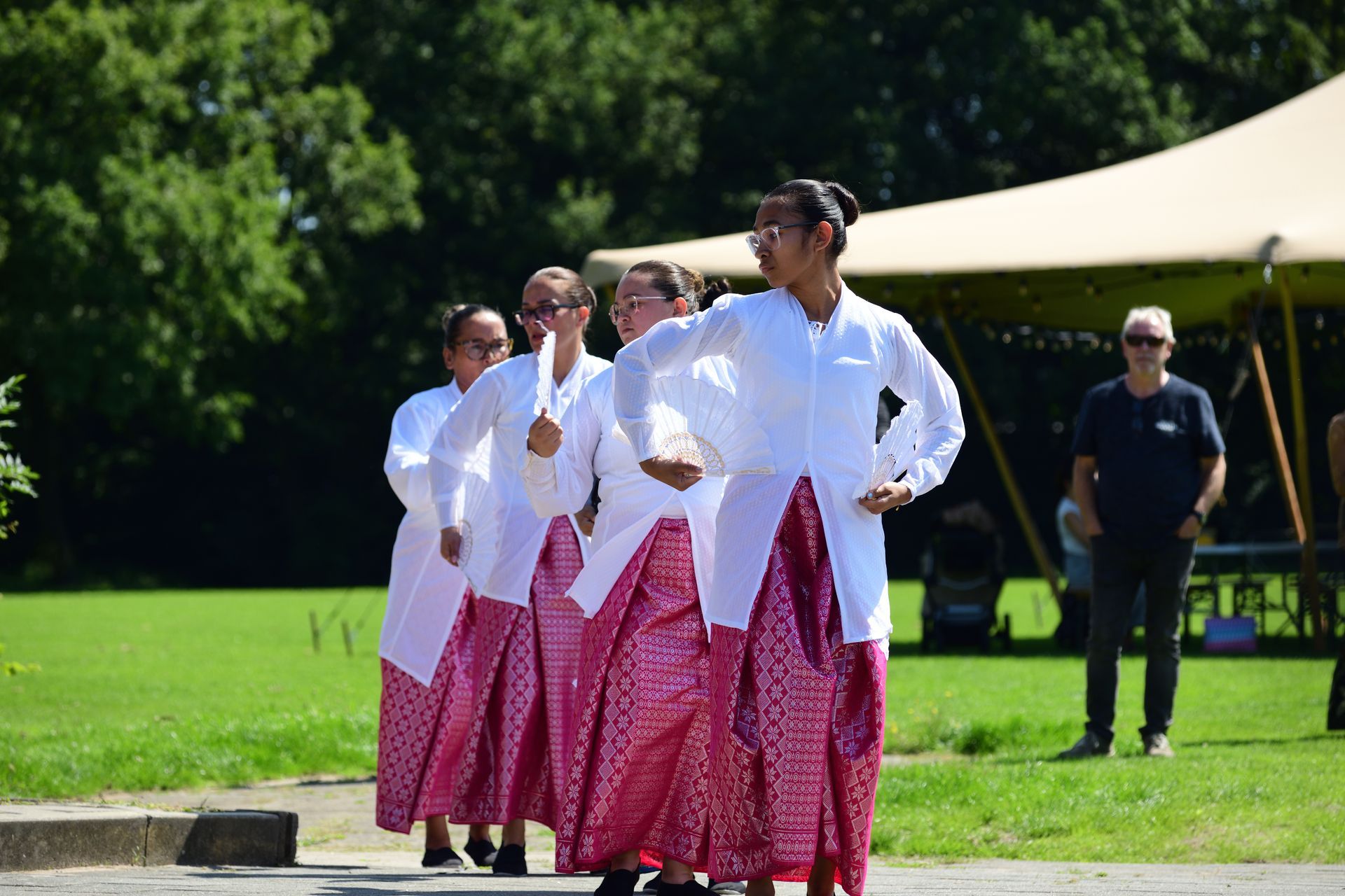 Een groep vrouwen danst voor een tent in een park.