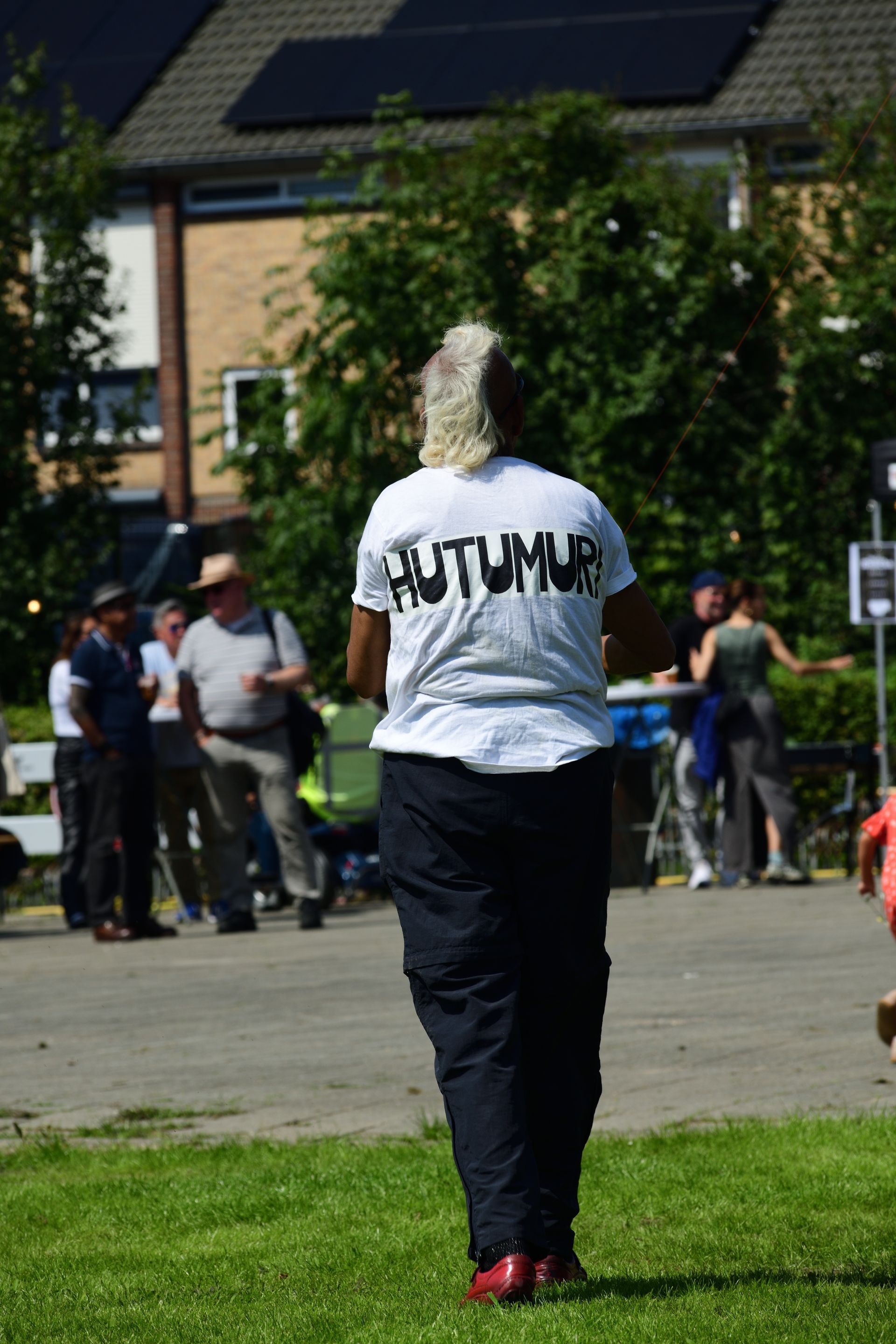 Een vrouw, gekleed in een wit overhemd met het woord herfst op de rug, loopt in een park.