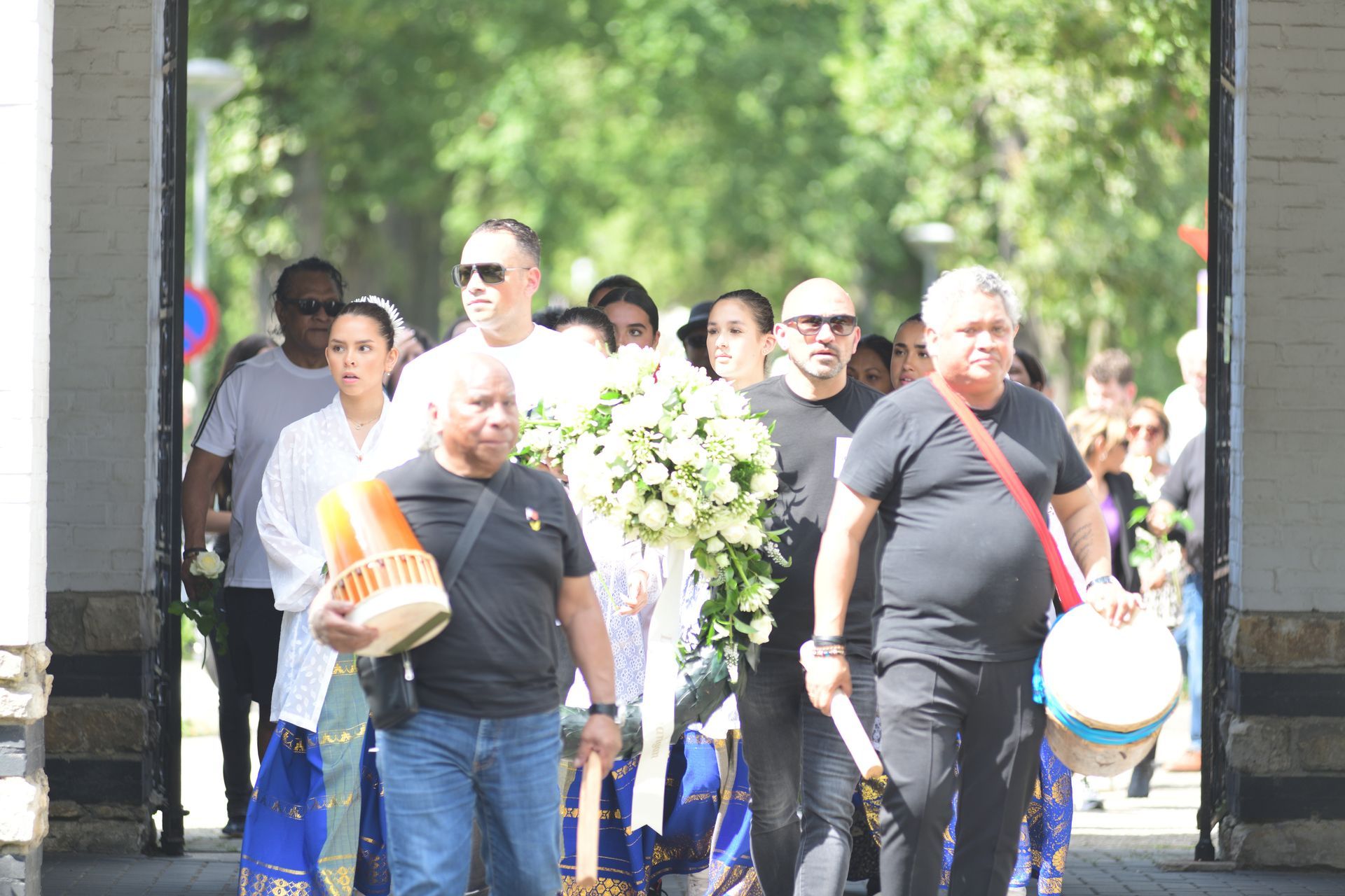 Een groep mensen loopt door de straat met bloemen in de hand.