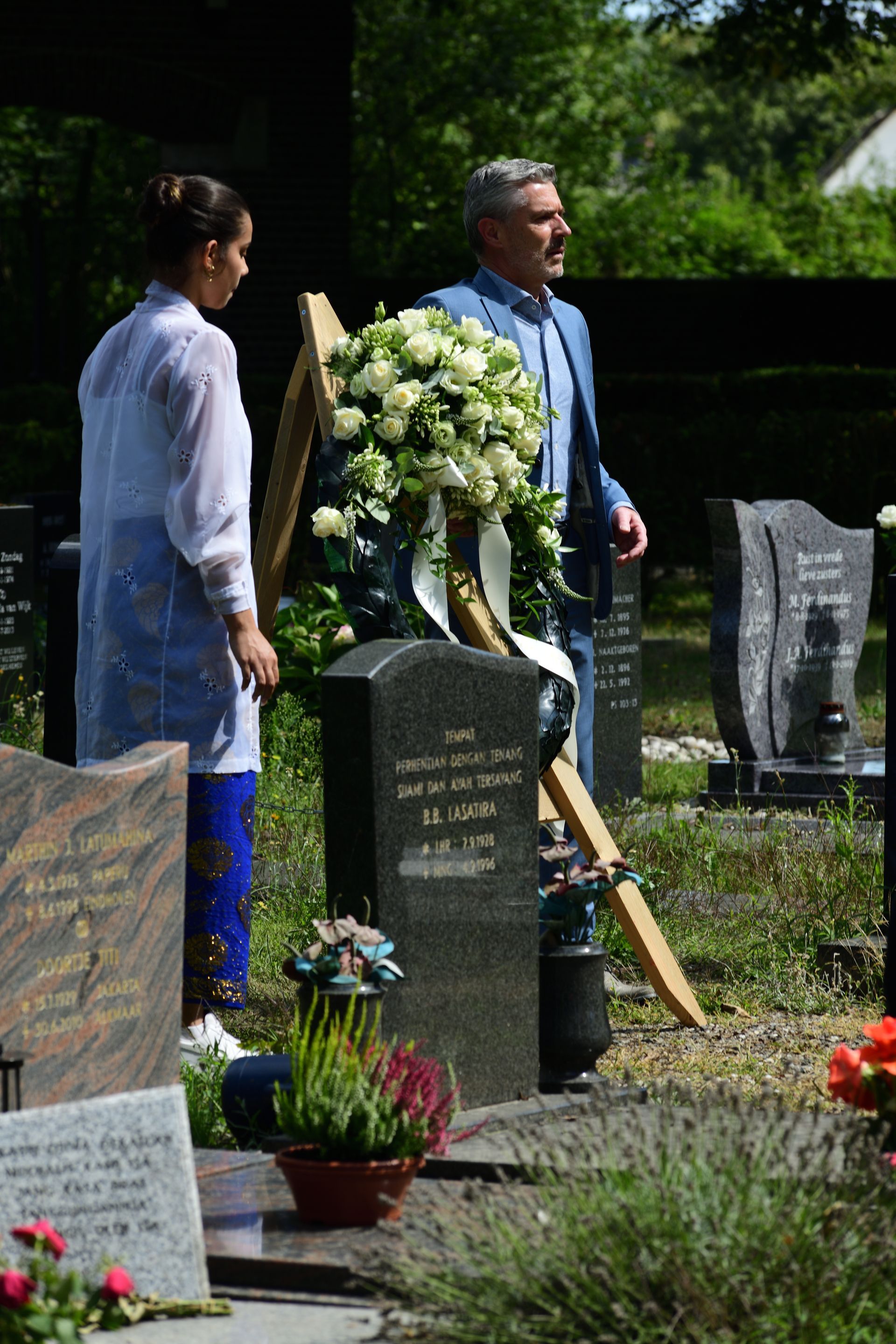 Een man en een vrouw staan ​​op een begraafplaats naast een graf.