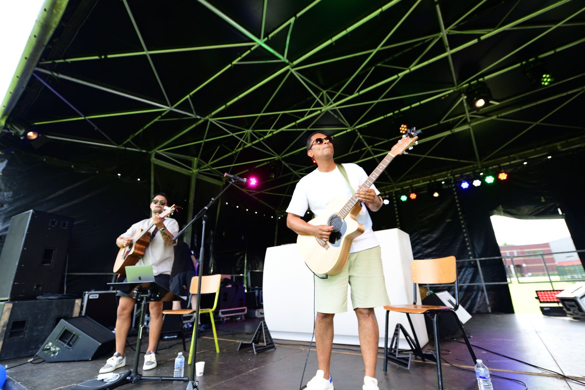 Twee mannen spelen gitaar op een podium.
