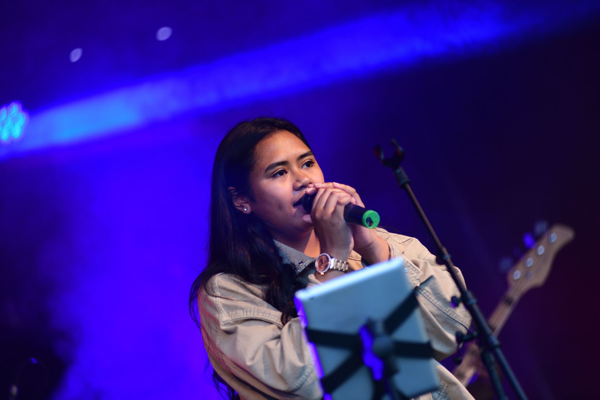 Een vrouw zingt in een microfoon op een podium.