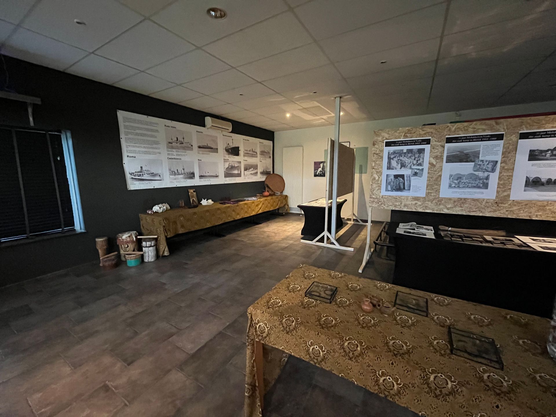 Een kamer met veel foto's aan de muur en een tafel.