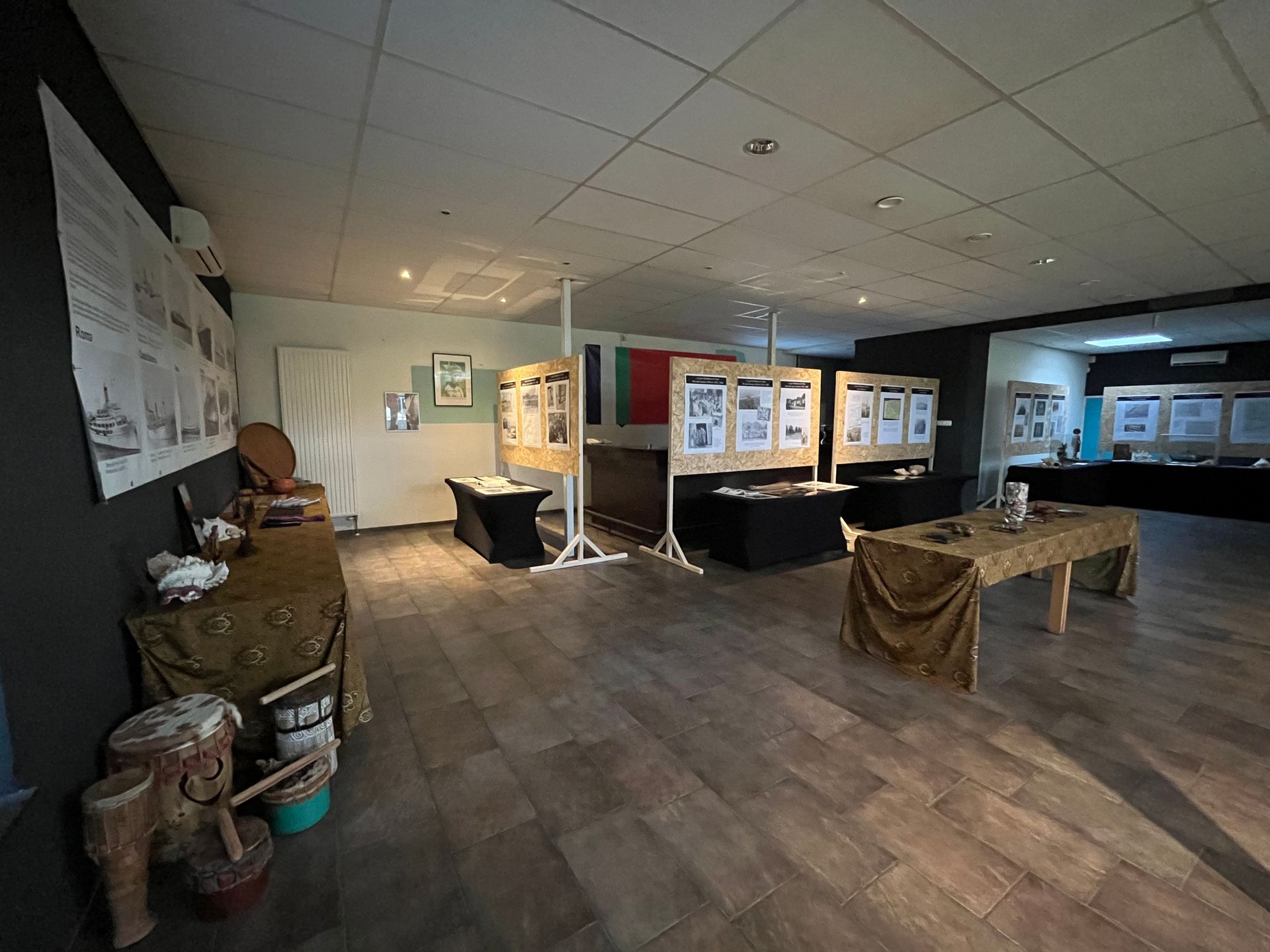 Een grote kamer met houten vloeren en veel tafels en stoelen.