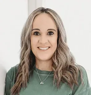 A woman wearing a white off the shoulder top and black jeans